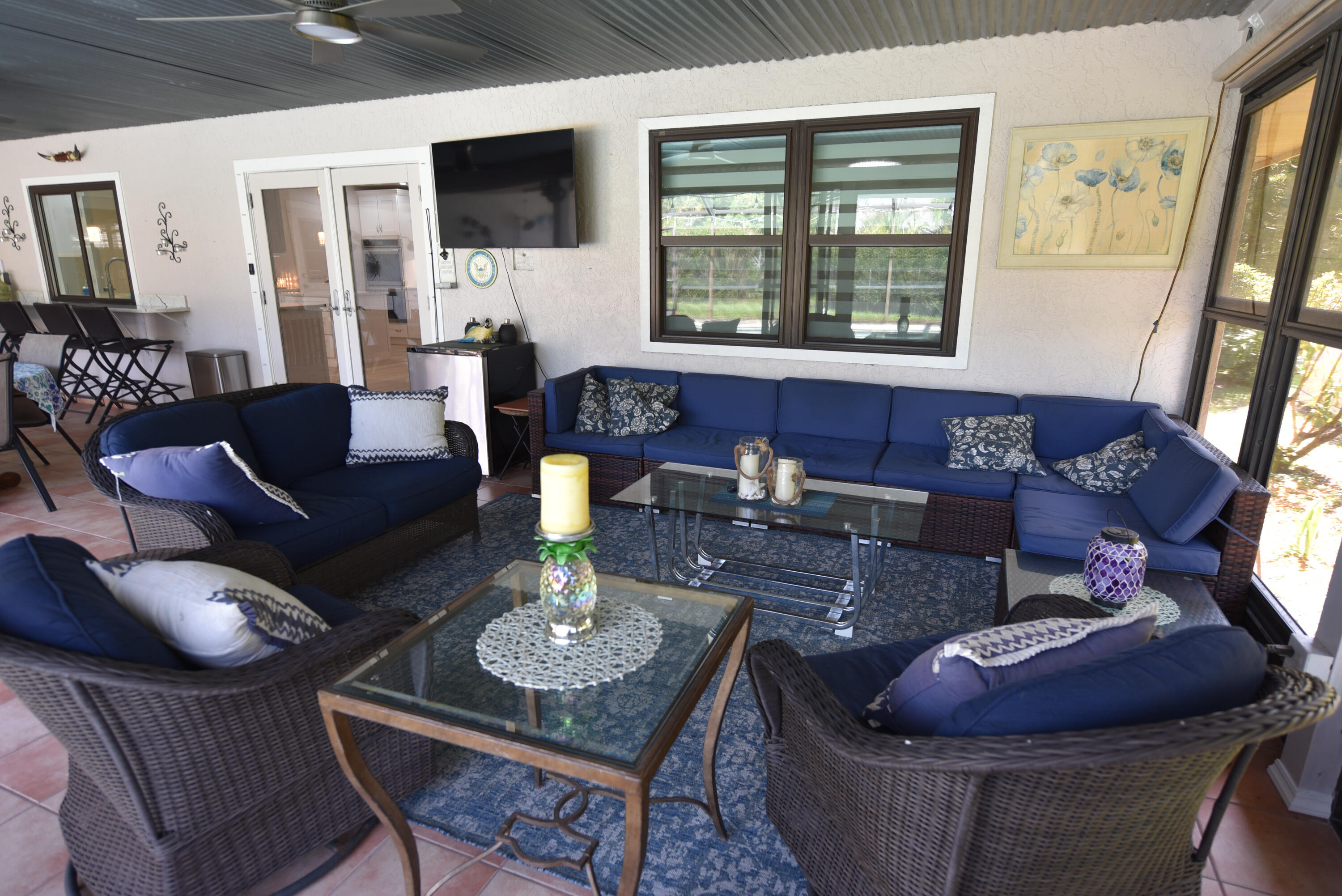 An inviting covered lanai designed for relaxation and entertaining, complete with comfortable seating and an outdoor TV. Perfect for enjoying the Florida lifestyle!