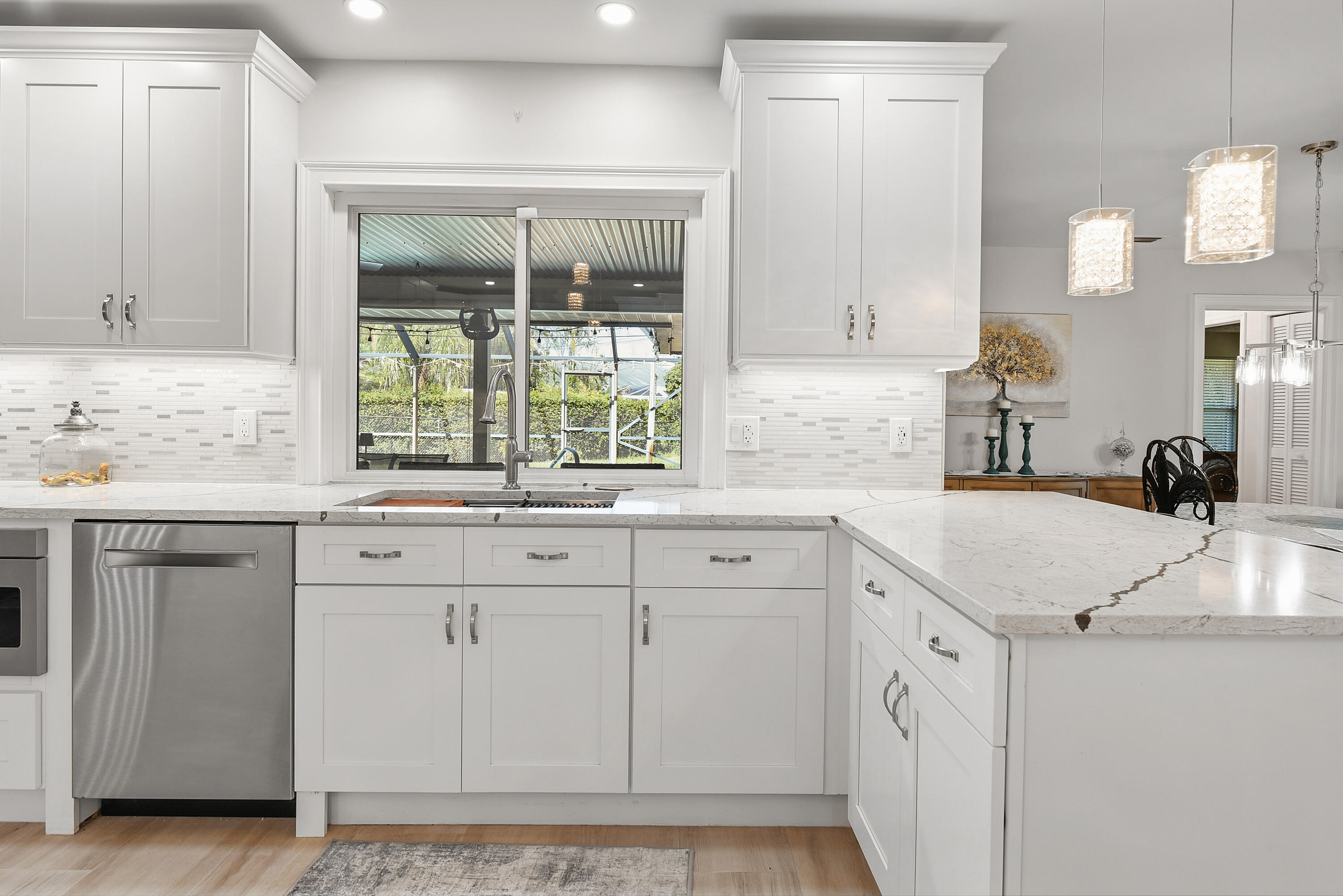 Beautiful decorative mosaic tile backsplash complements the marble-look countertops and crisp white cabinetry. The double-basin stainless steel sink with high-arc faucet adds both style and functionality to this gorgeous kitchen!