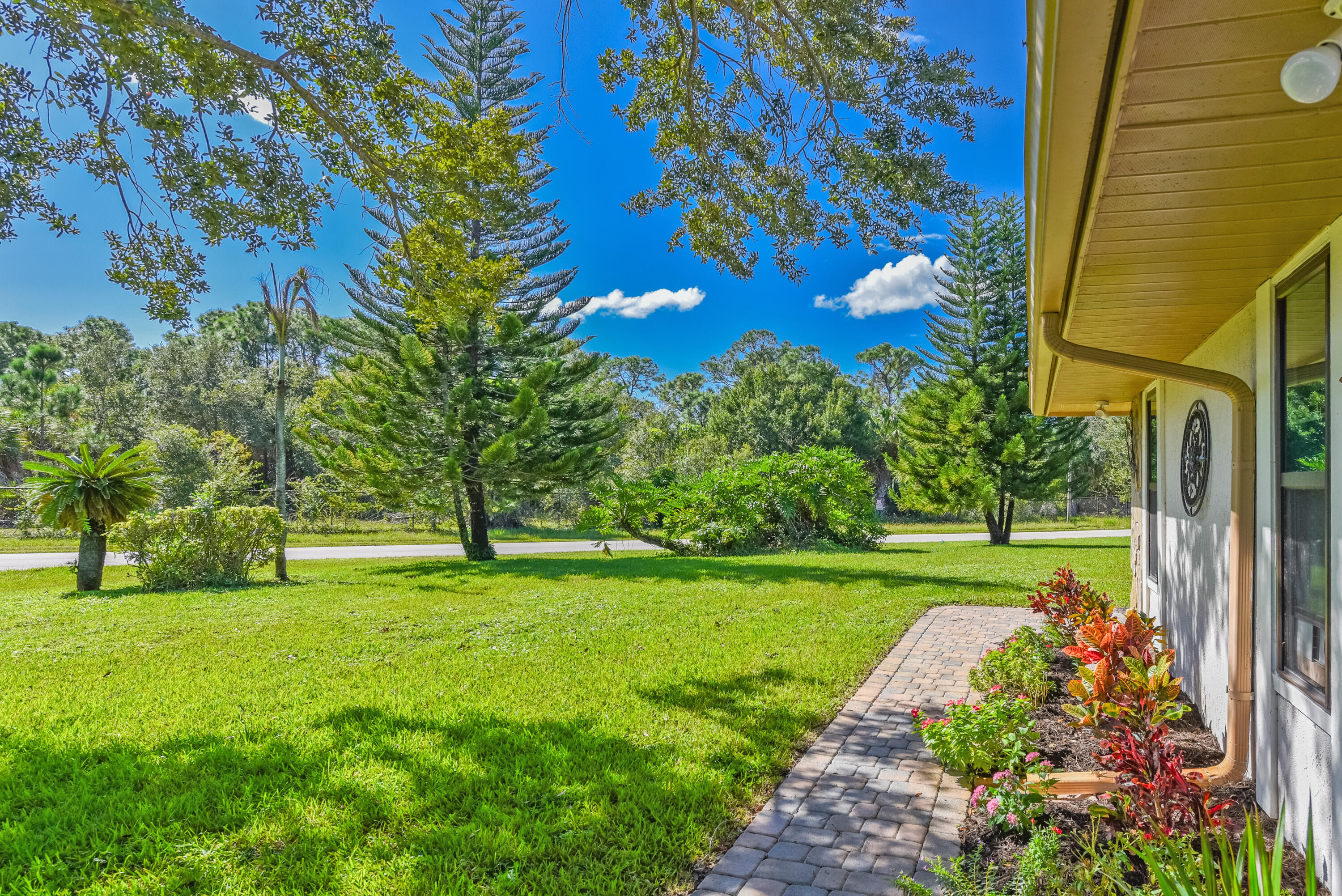 Enjoy the expansive green lawn, mature trees, colorful tropical plantings, and charming paver walkway