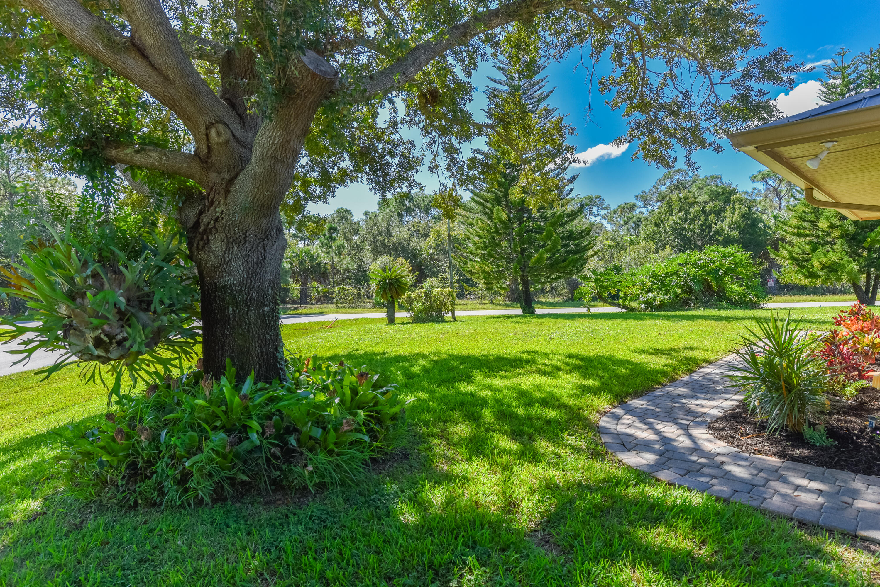 Beautifully landscaped grounds featuring majestic shade trees, lush greenery, and an inviting lawn. Enjoy the natural beauty and peaceful setting of this nearly half-acre Sandpiper Bay property!