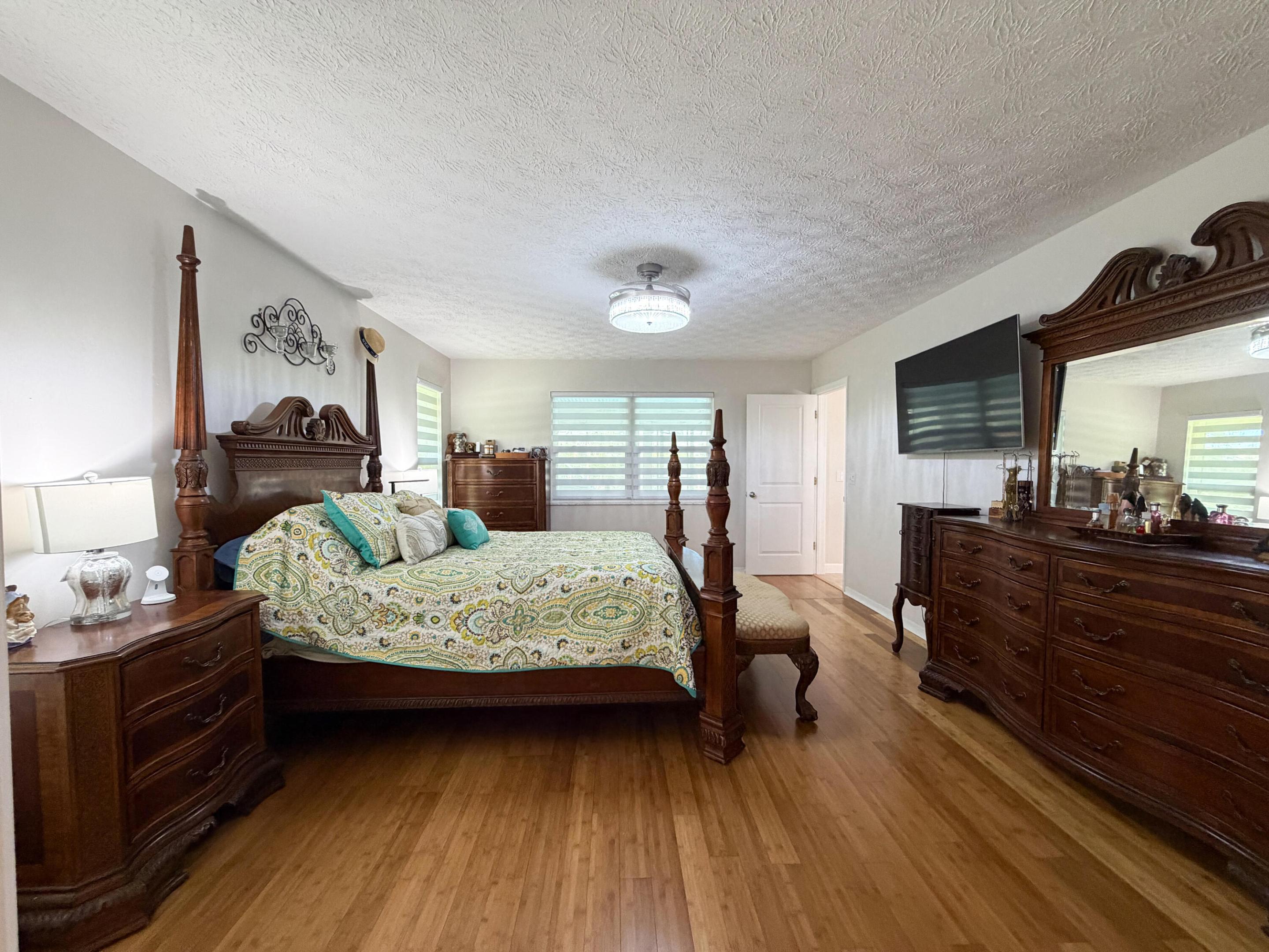 Generously sized primary bedroom featuring beautiful bamboo flooring, stylish window treatments, and plenty of room for oversized furniture.