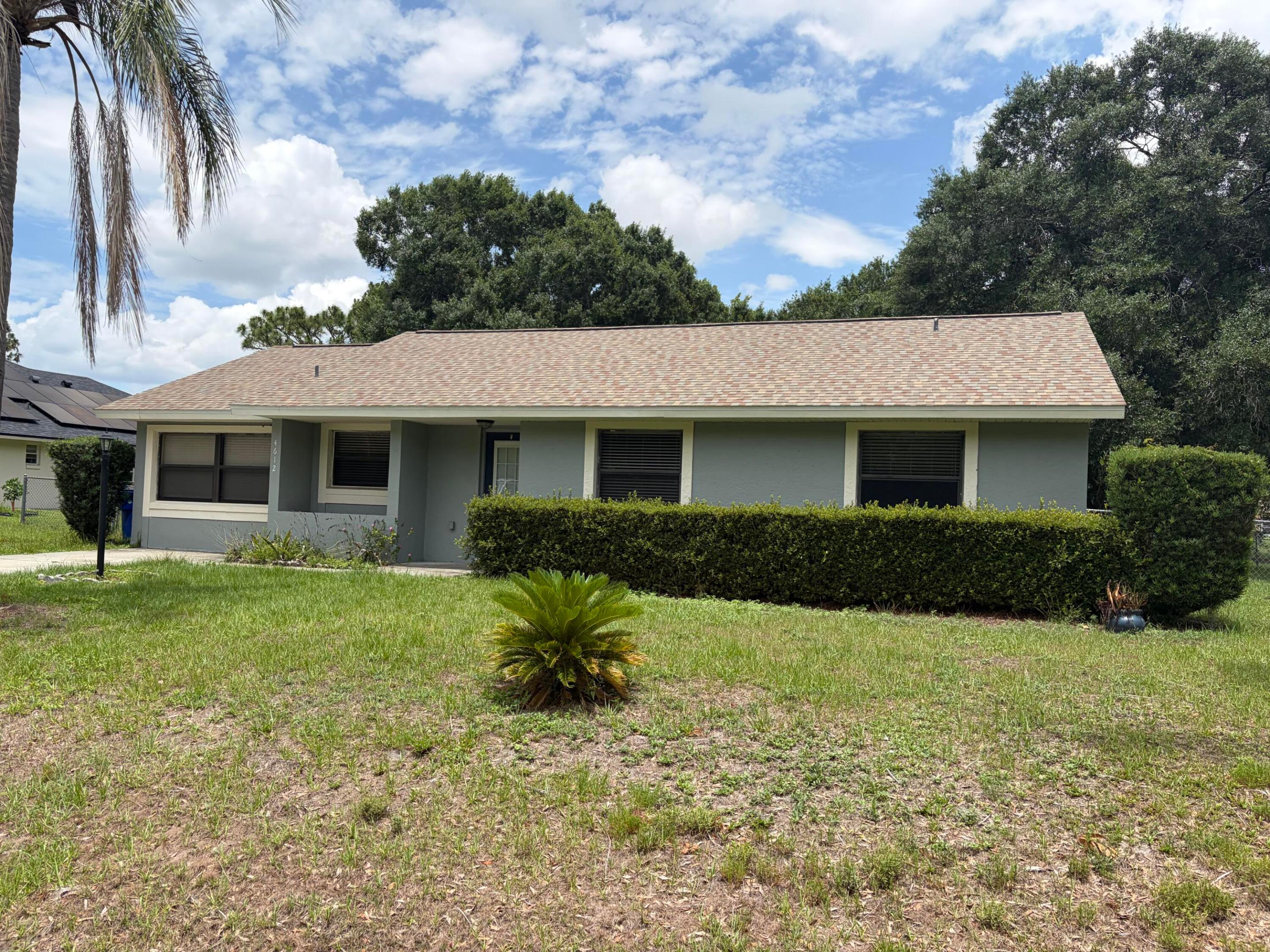 Single-story exterior featuring a shingled roof, neutral-toned siding, and established landscaping with manicured shrubbery Single-story exterior featuring a shingled roof, neutral-toned siding, and established landscaping with manicured shrubbery