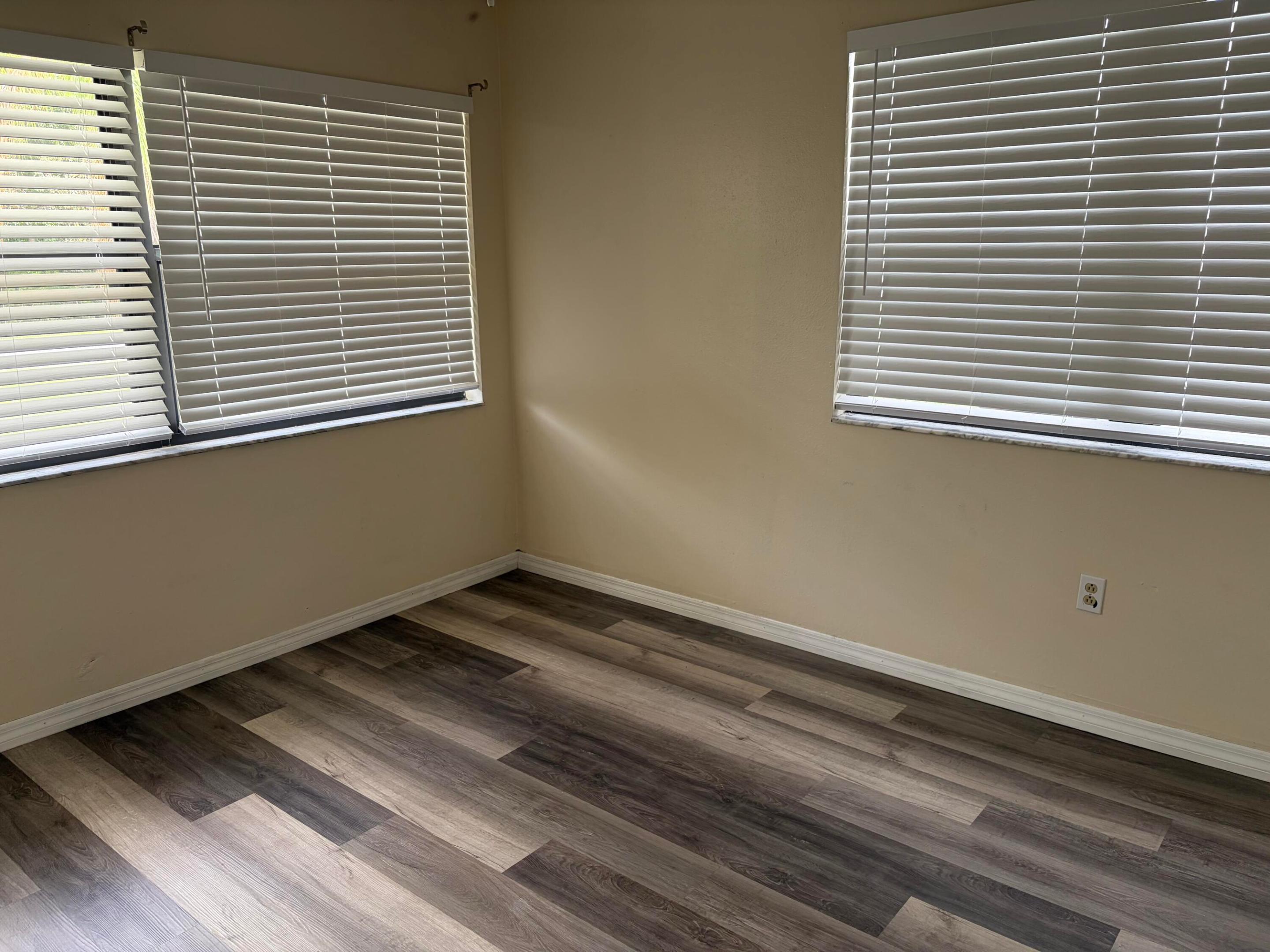 Wood-finish flooring paired with neutral wall tones and horizontal window blinds