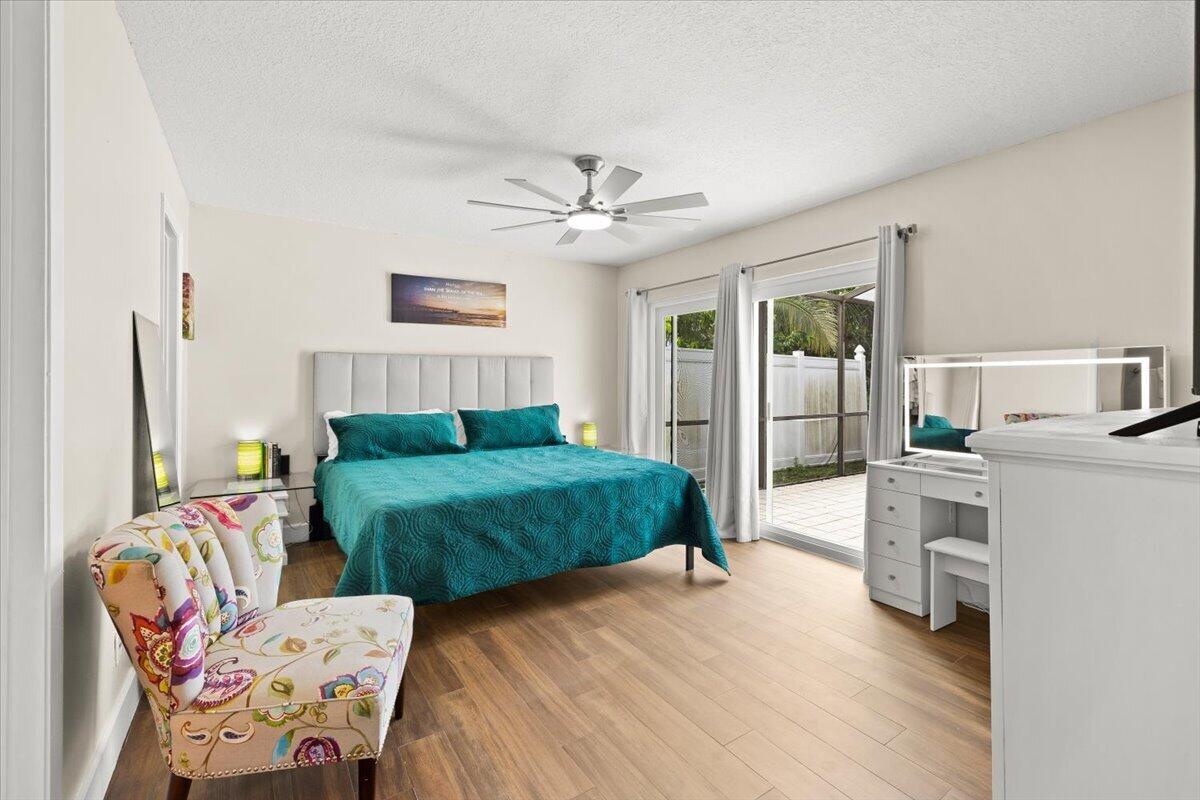 Spacious room featuring wood-finish flooring, a ceiling fan with integrated lighting, and sliding glass doors with access to an exterior screened enclosure