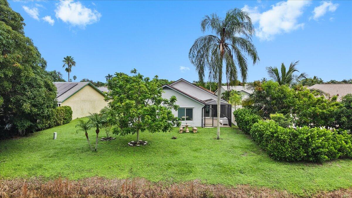 Expansive backyard featuring a sprawling lawn, mature trees, dense privacy hedges, and a screened rear porch