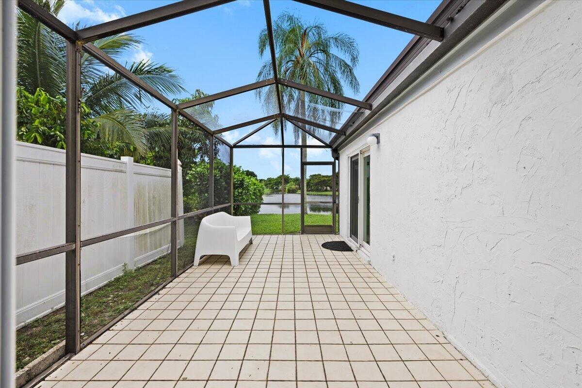Screen-enclosed lanai featuring a tile floor, textured white exterior wall, and access to a water feature