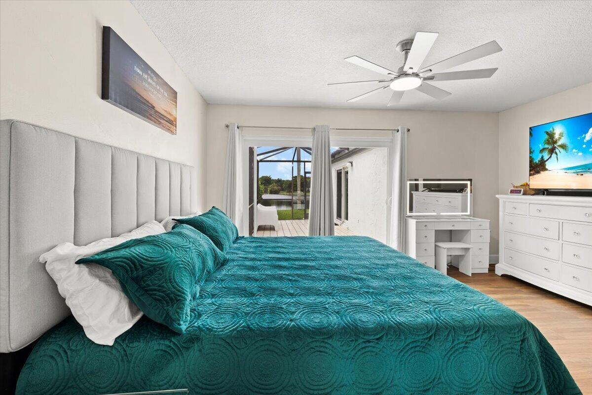 Wood-finish flooring, multi-blade ceiling fan with integrated lighting, and glass sliding doors featuring a screen-enclosed exterior area