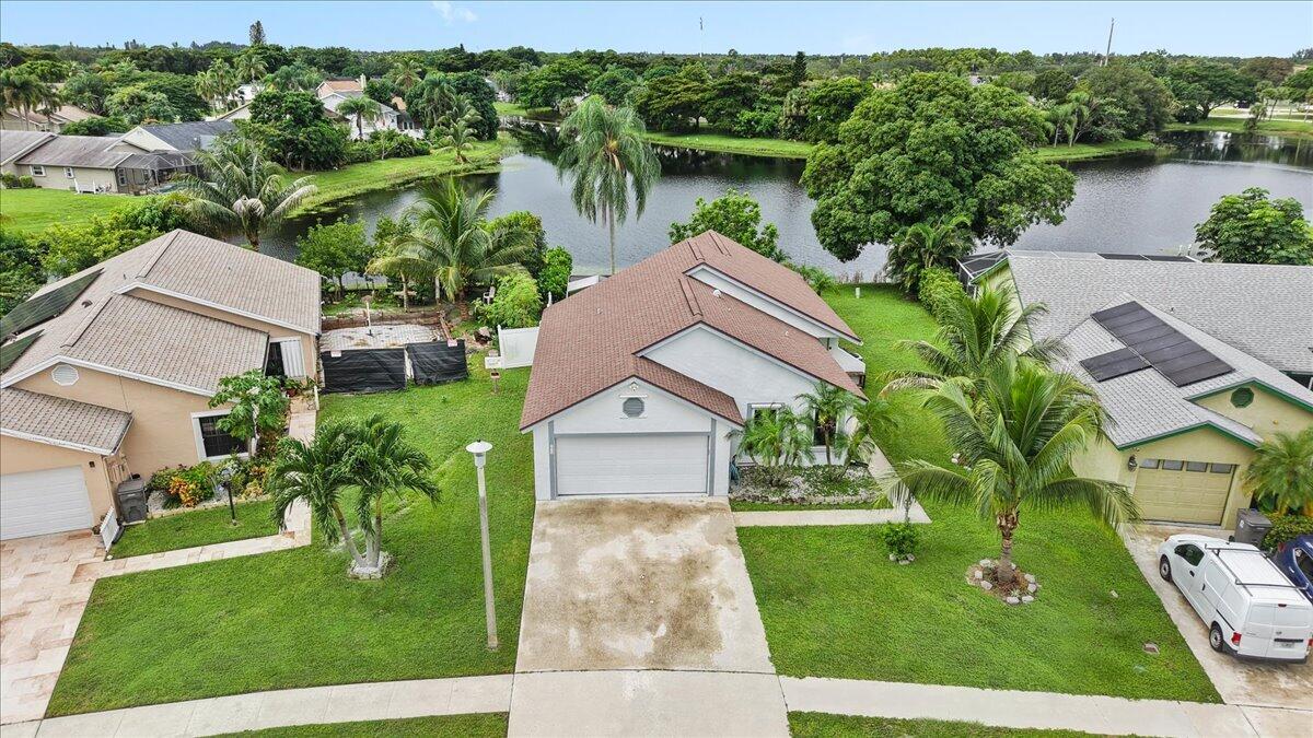 Single-story residence featuring a gabled roof, attached two-car garage, concrete driveway, and backyard waterfront access