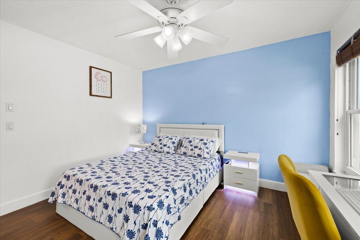 Wood-finish flooring, accent wall, and ceiling fan with integrated light fixture