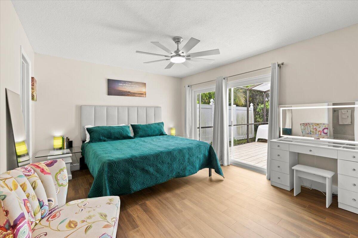 Wood-finish flooring, ceiling fan with integrated lighting, and sliding glass doors with access to an exterior screened enclosure