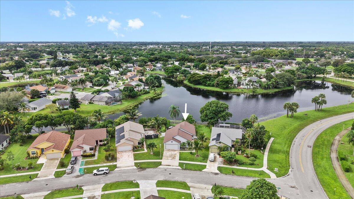 Aerial perspective featuring a single-story residence with a multi-gable roofline, attached two-car garage, solar panels, and waterfront positioning