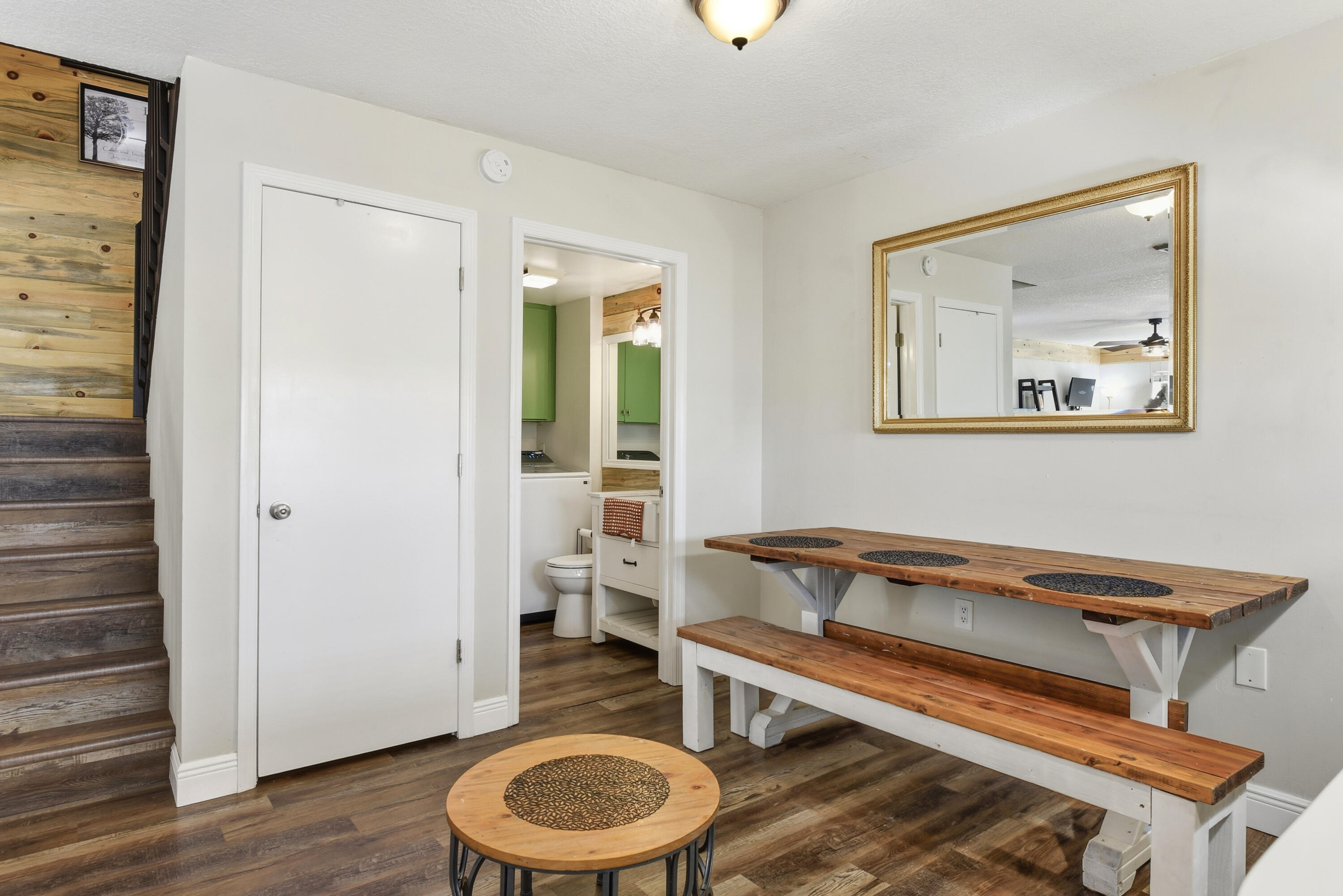 Wood-finish flooring, staircase with natural wood accent wall, and ceiling-mounted light fixture