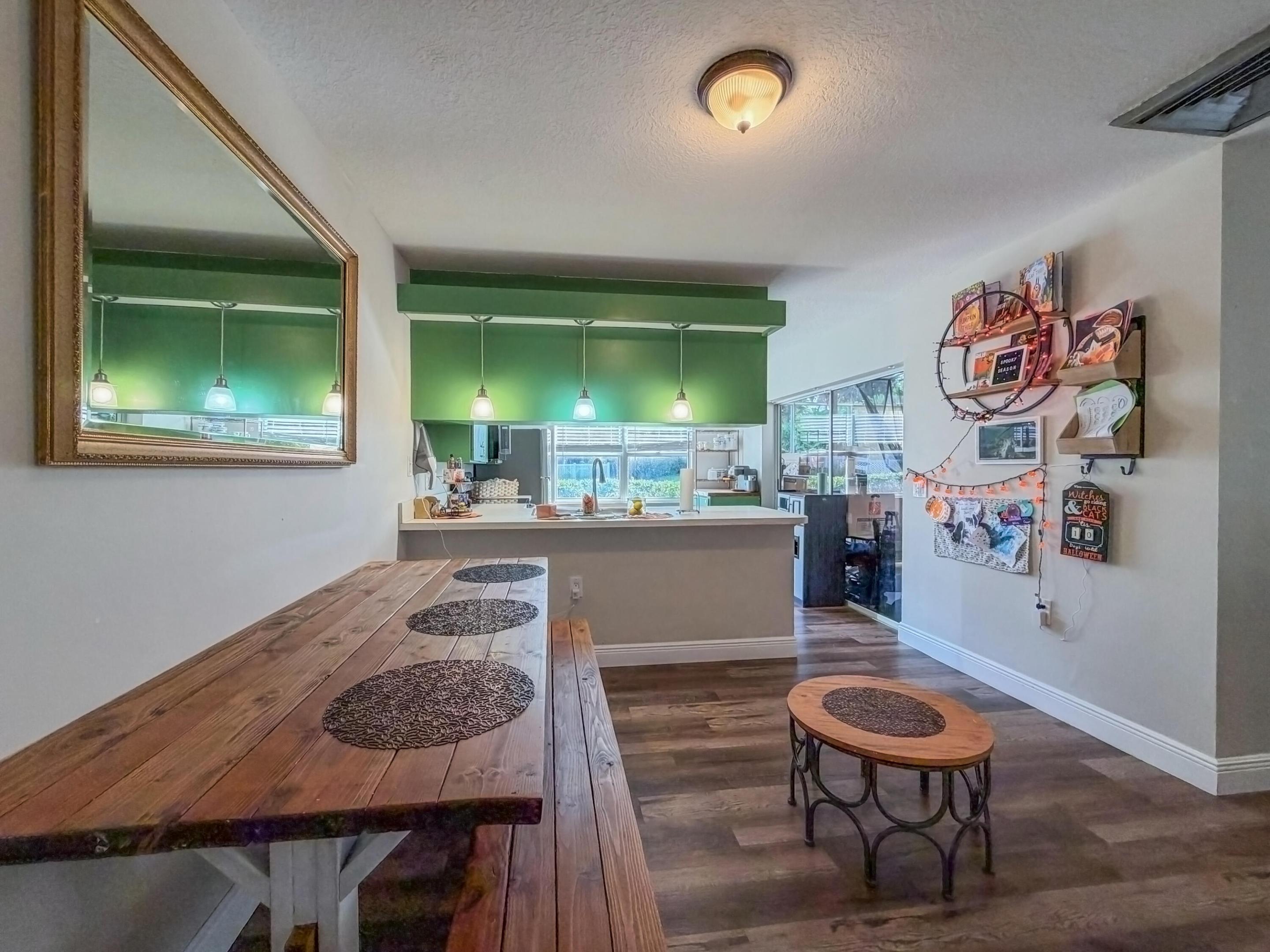 Wood-finish flooring, kitchen peninsula with overhead pendant lighting, and wall-mounted mirror