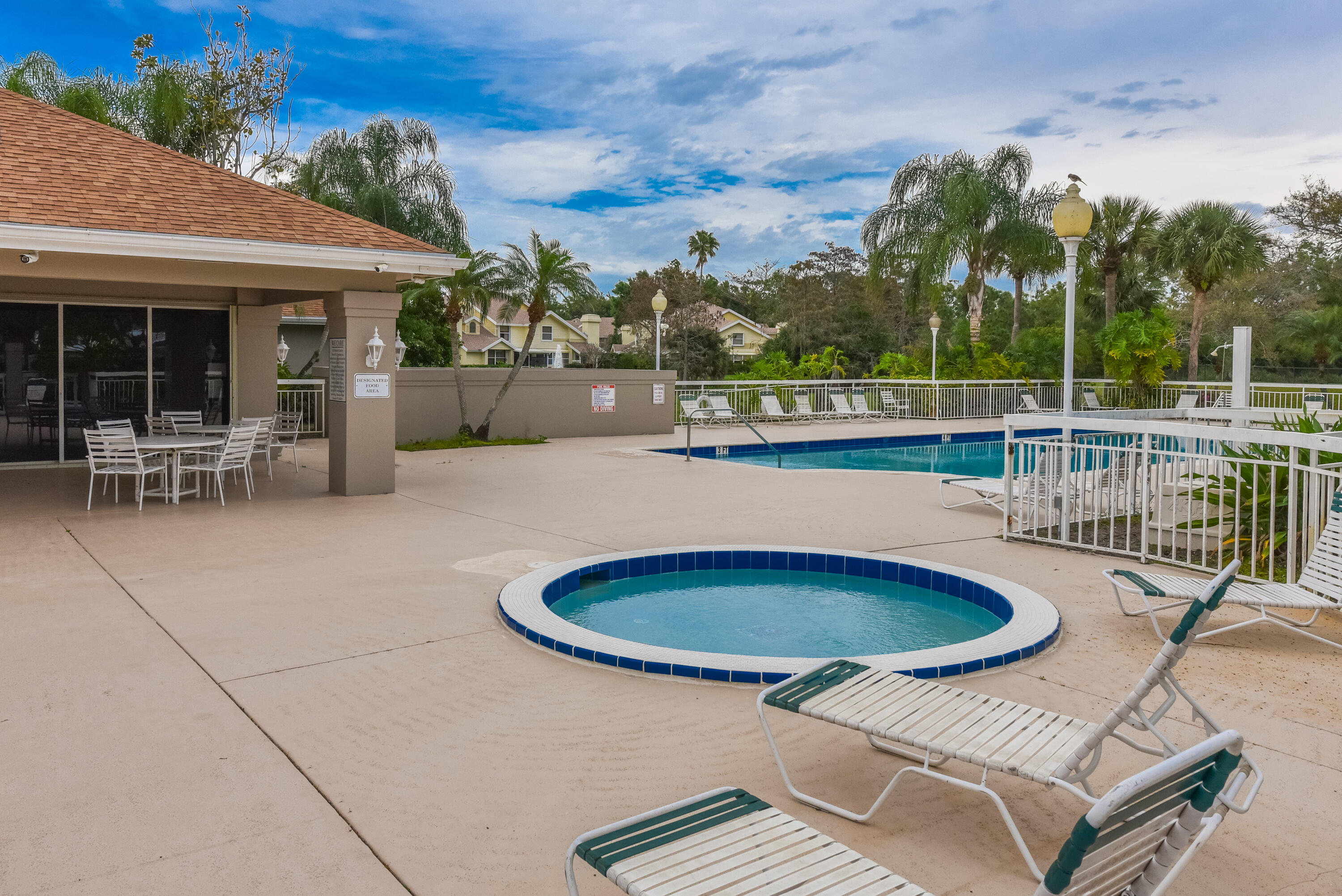 Outdoor swimming pool and circular spa featuring concrete decking, perimeter fencing, and covered patio space