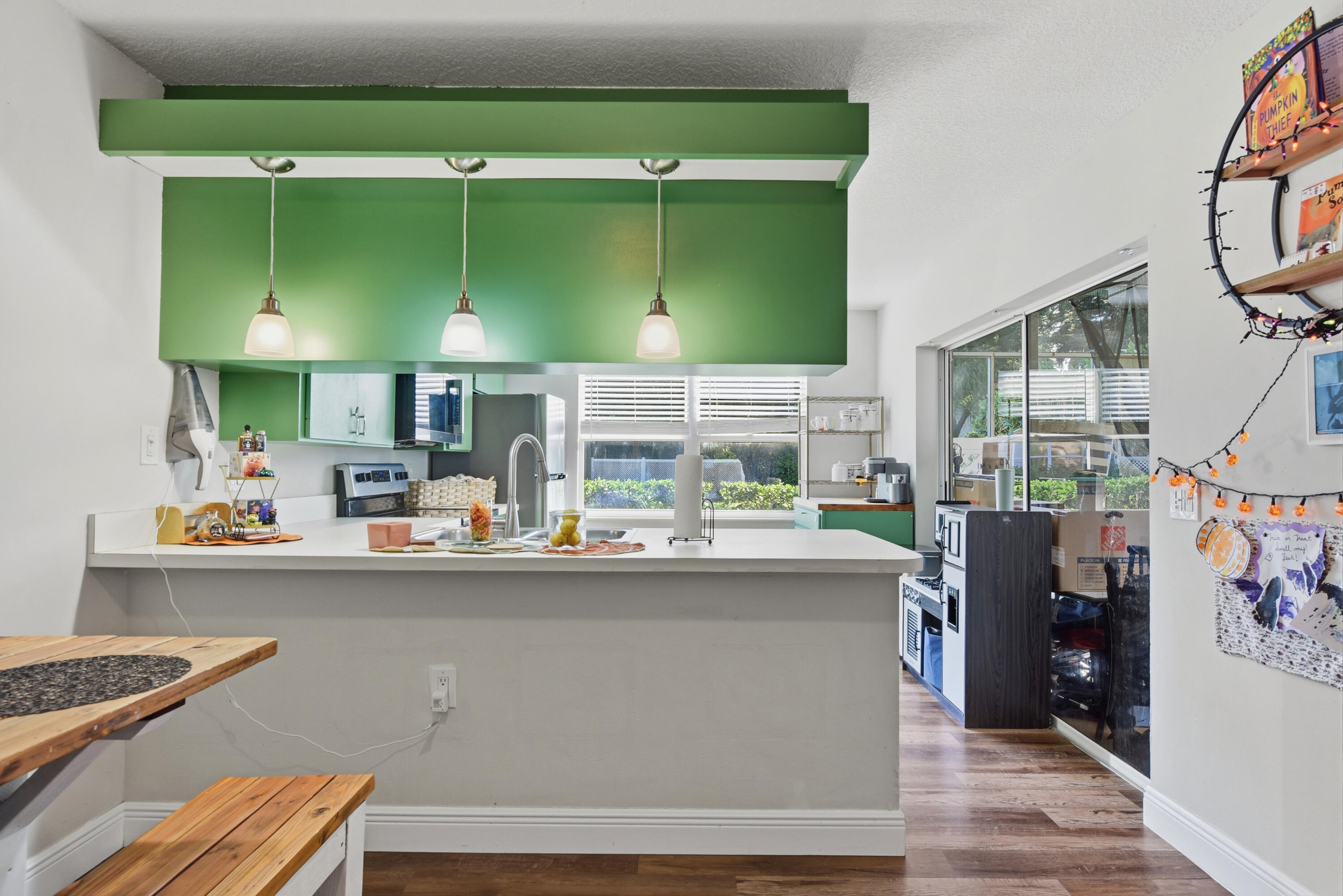 Kitchen featuring a peninsula breakfast bar, solid surface countertops, a stainless steel undermount sink, three pendant lights, and wood-finish flooring