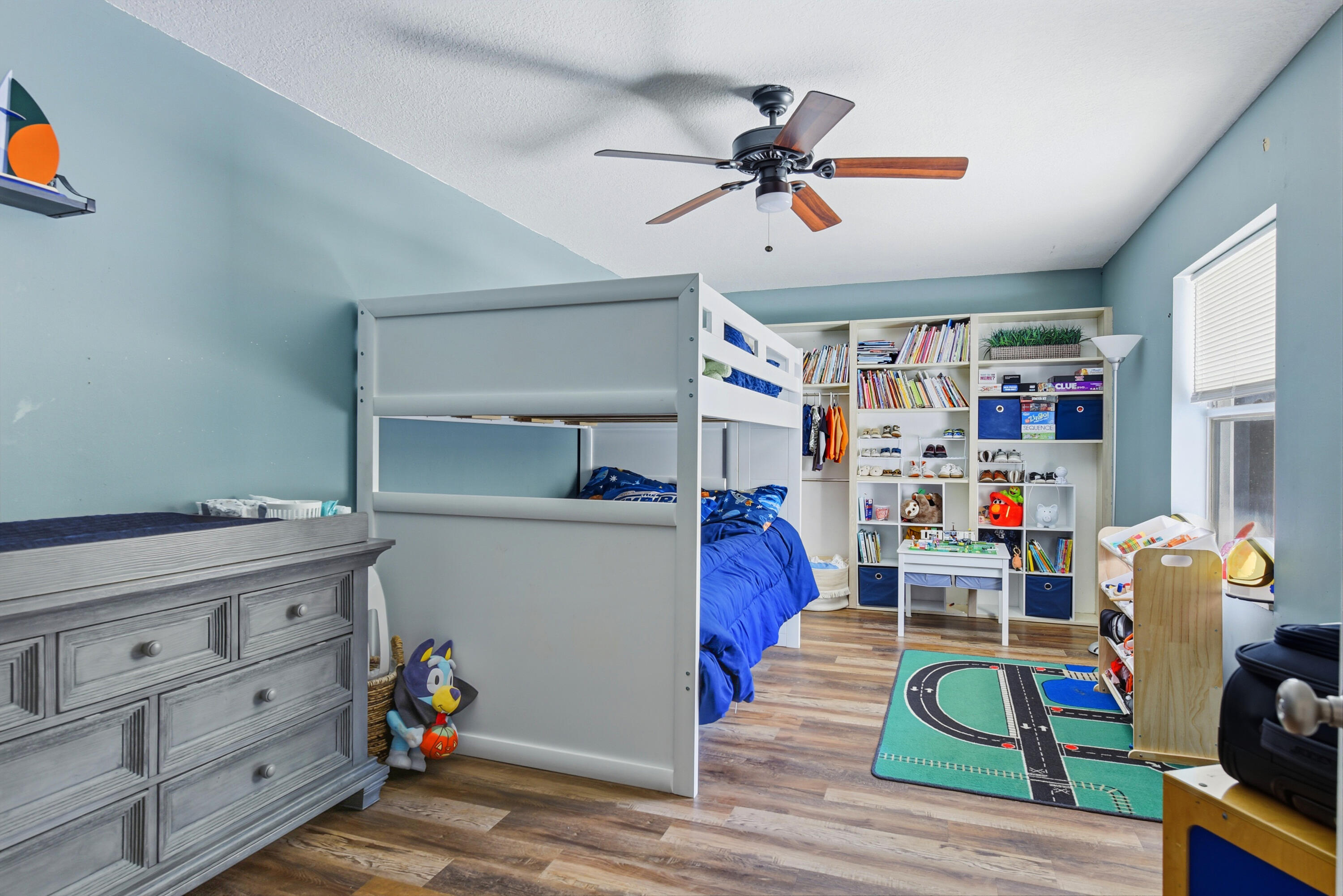 Wood-finish flooring, ceiling fan with integrated lighting, and custom built-in floor-to-ceiling shelving unit