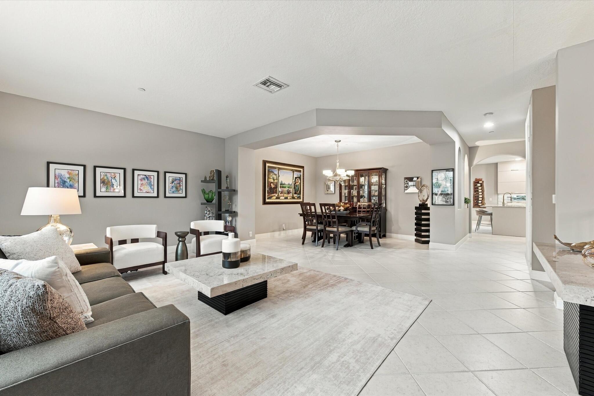 Living area featuring neutral wall tones, large-format tile flooring, recessed lighting, and a distinct architectural recessed ceiling detail
