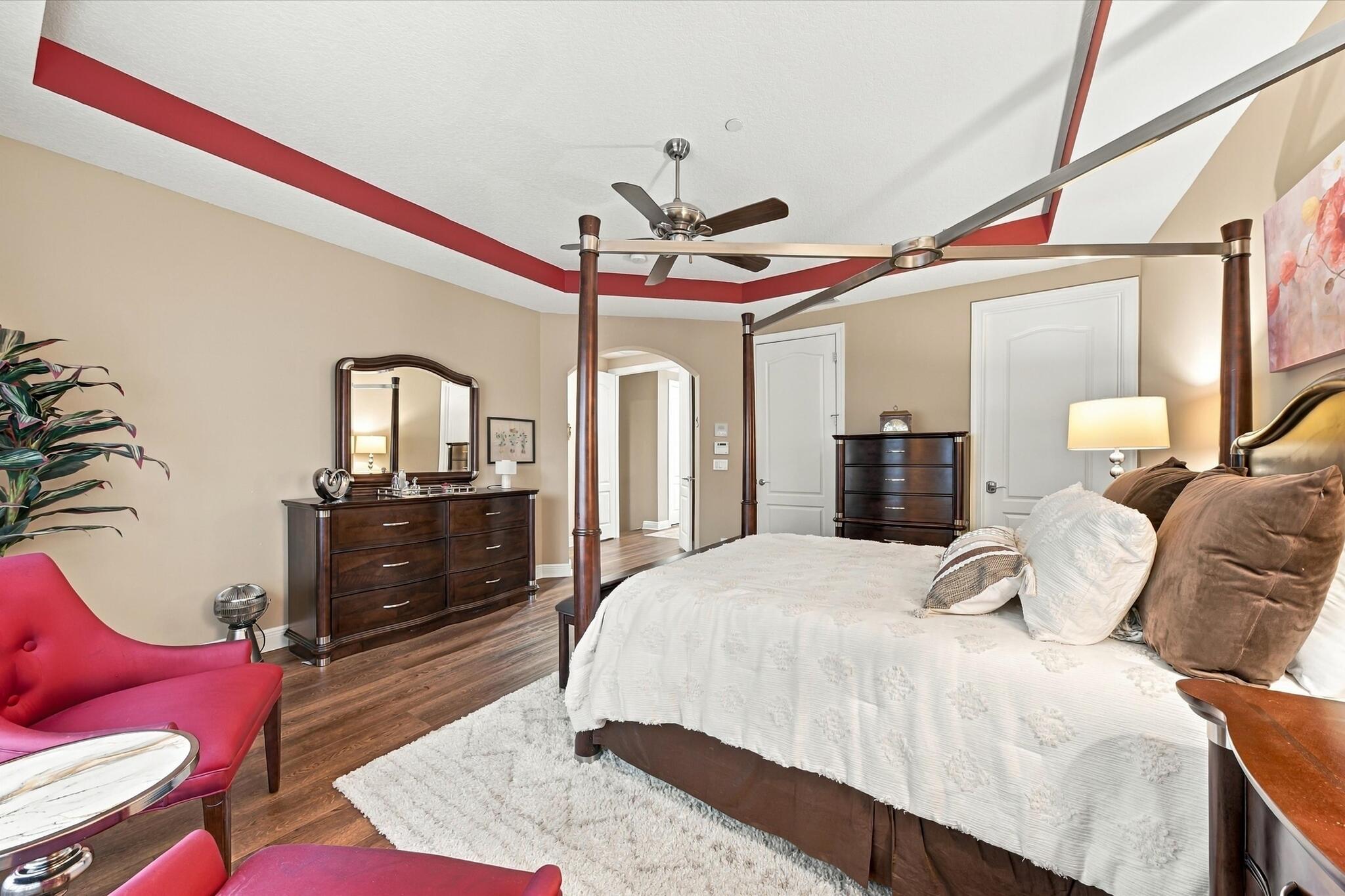 Room featuring tray ceiling with accent molding, wood-finish flooring, and a ceiling fan
