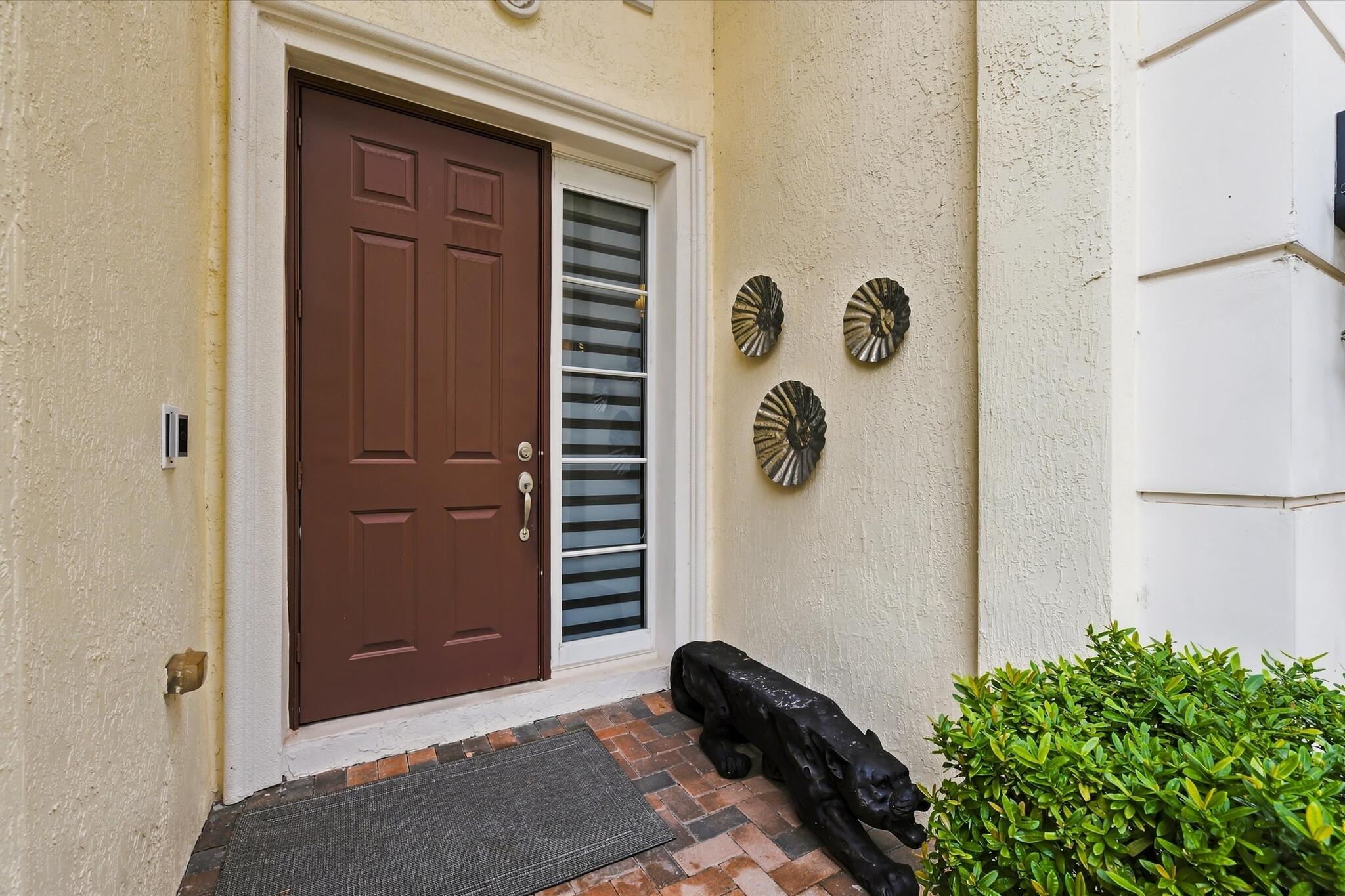 Entryway featuring a six-panel dark wood-finish door, vertical sidelight, stucco exterior finish, and brick paver flooring