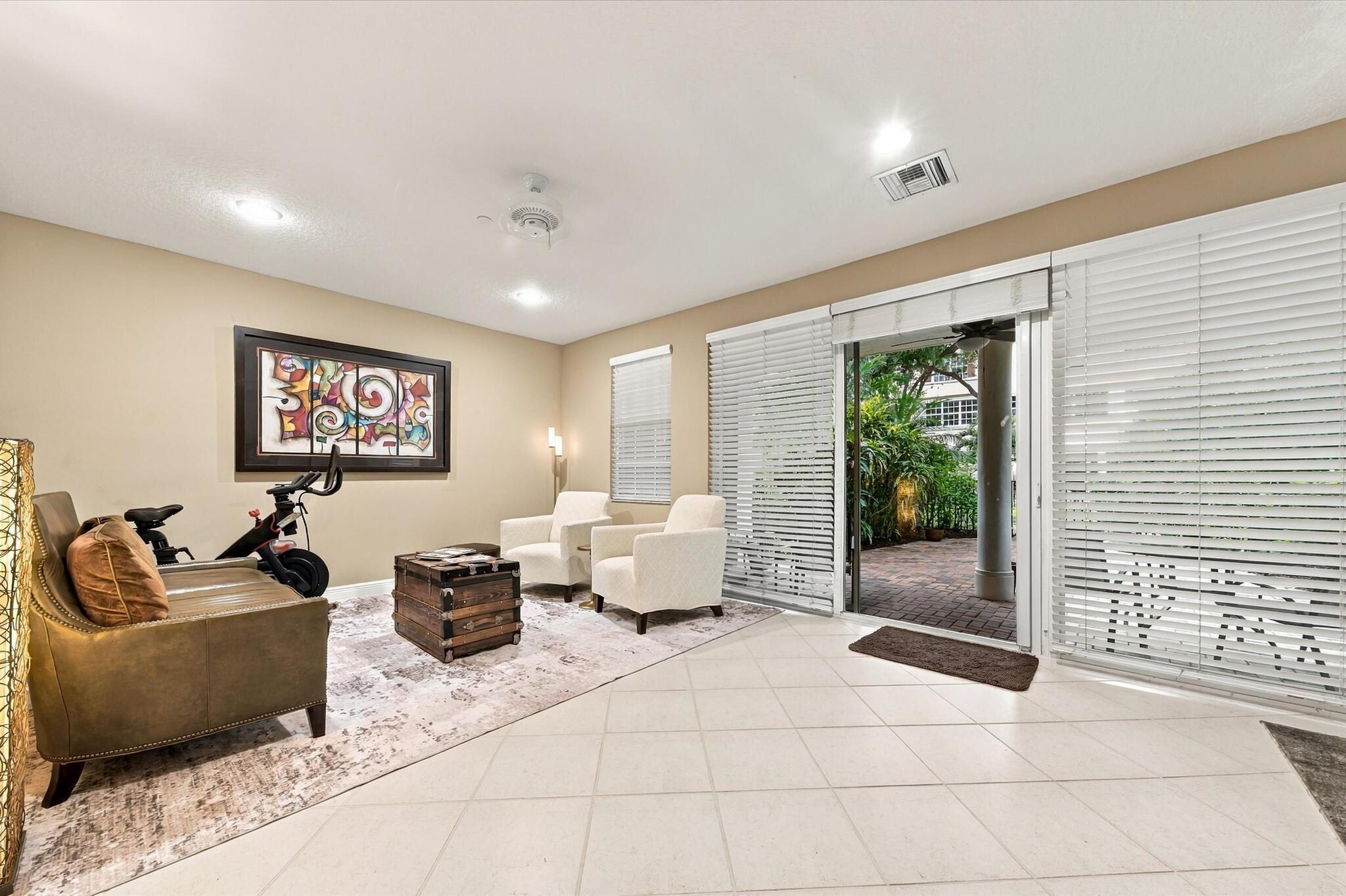 Large-format tile flooring, recessed lighting, ceiling fan, and sliding glass doors with horizontal blinds