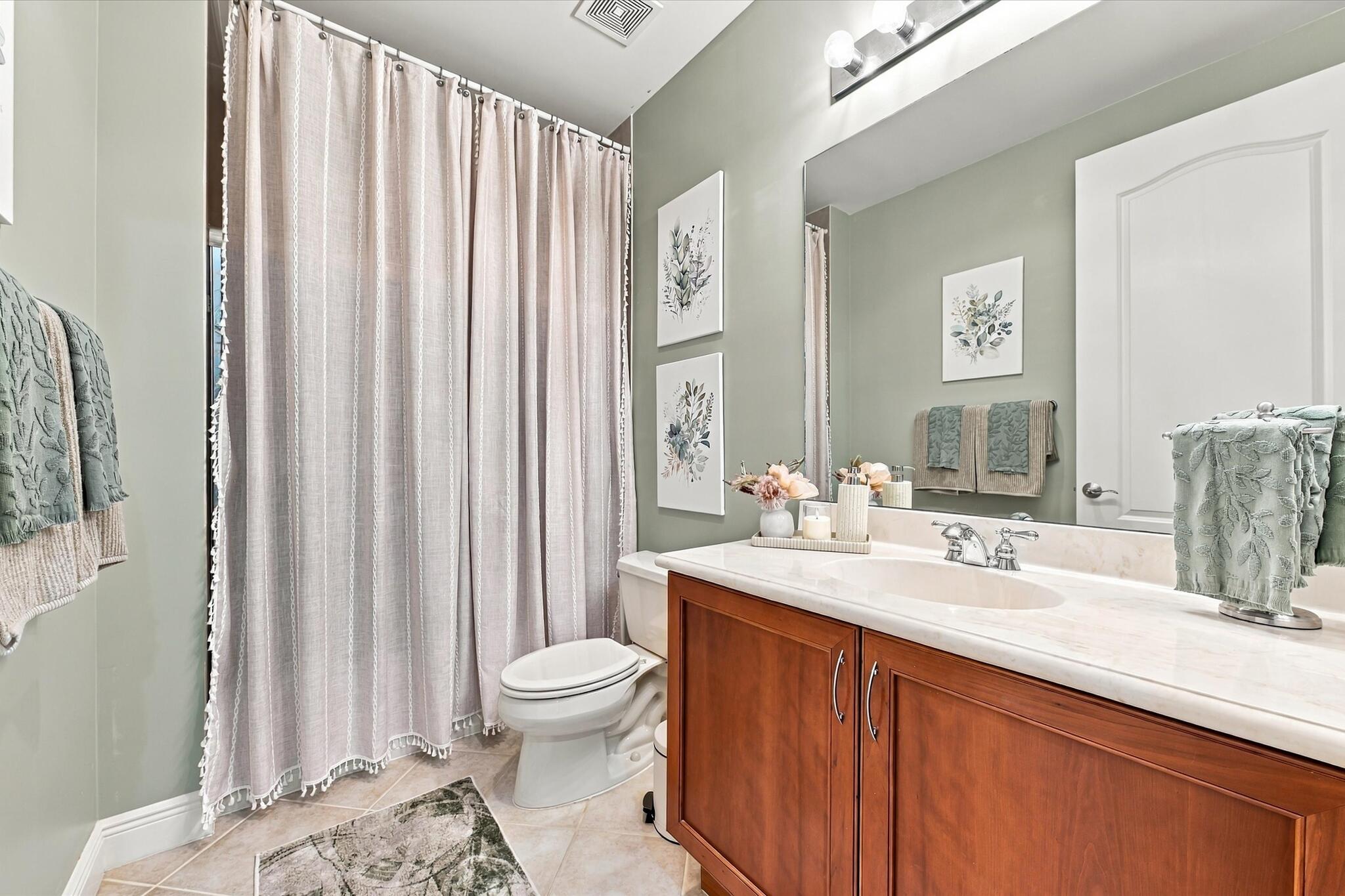 Full bathroom featuring a wood-finish vanity with a light-toned solid surface countertop, an integrated oval basin, a large wall-mounted mirror, and tile flooring