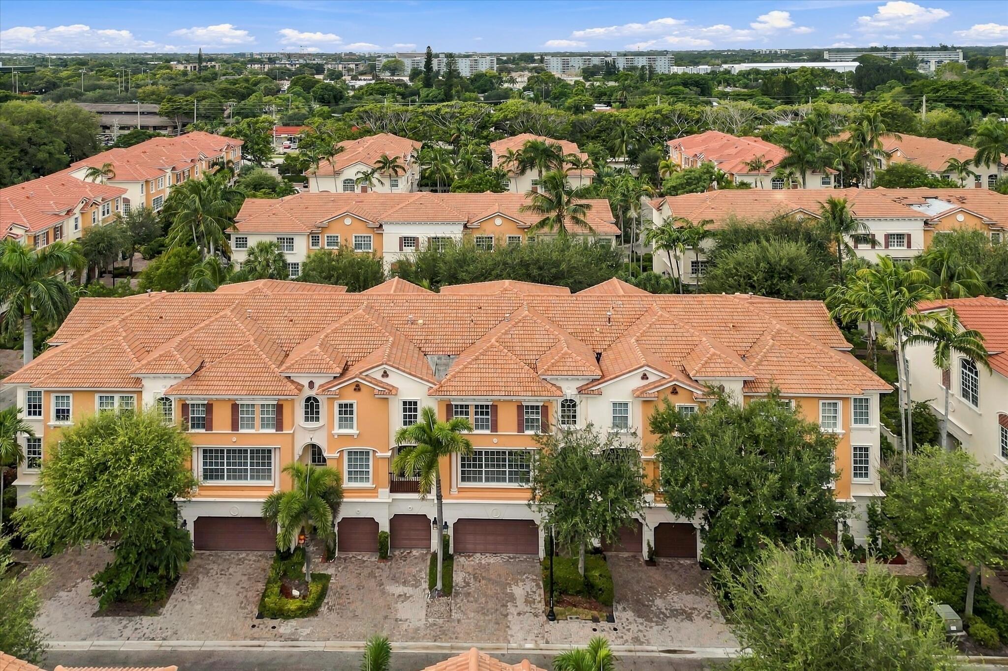 Multi-story residential complex featuring terracotta-style roofing, stucco exterior finish, multiple attached garages, and paver driveways