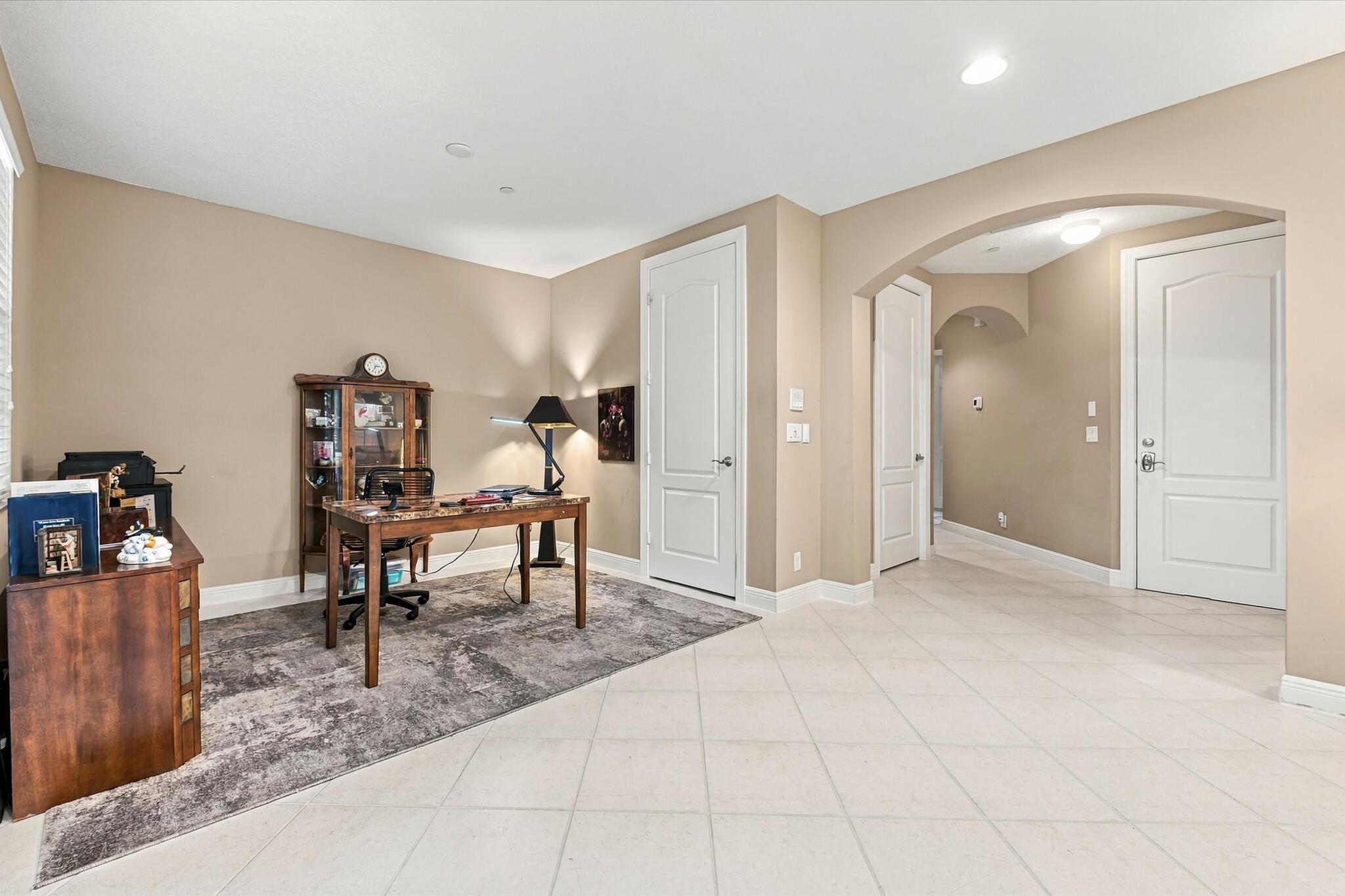 Neutral-toned interior featuring large-format diagonal tile flooring, arched architectural detailing, and multi-panel solid core doors