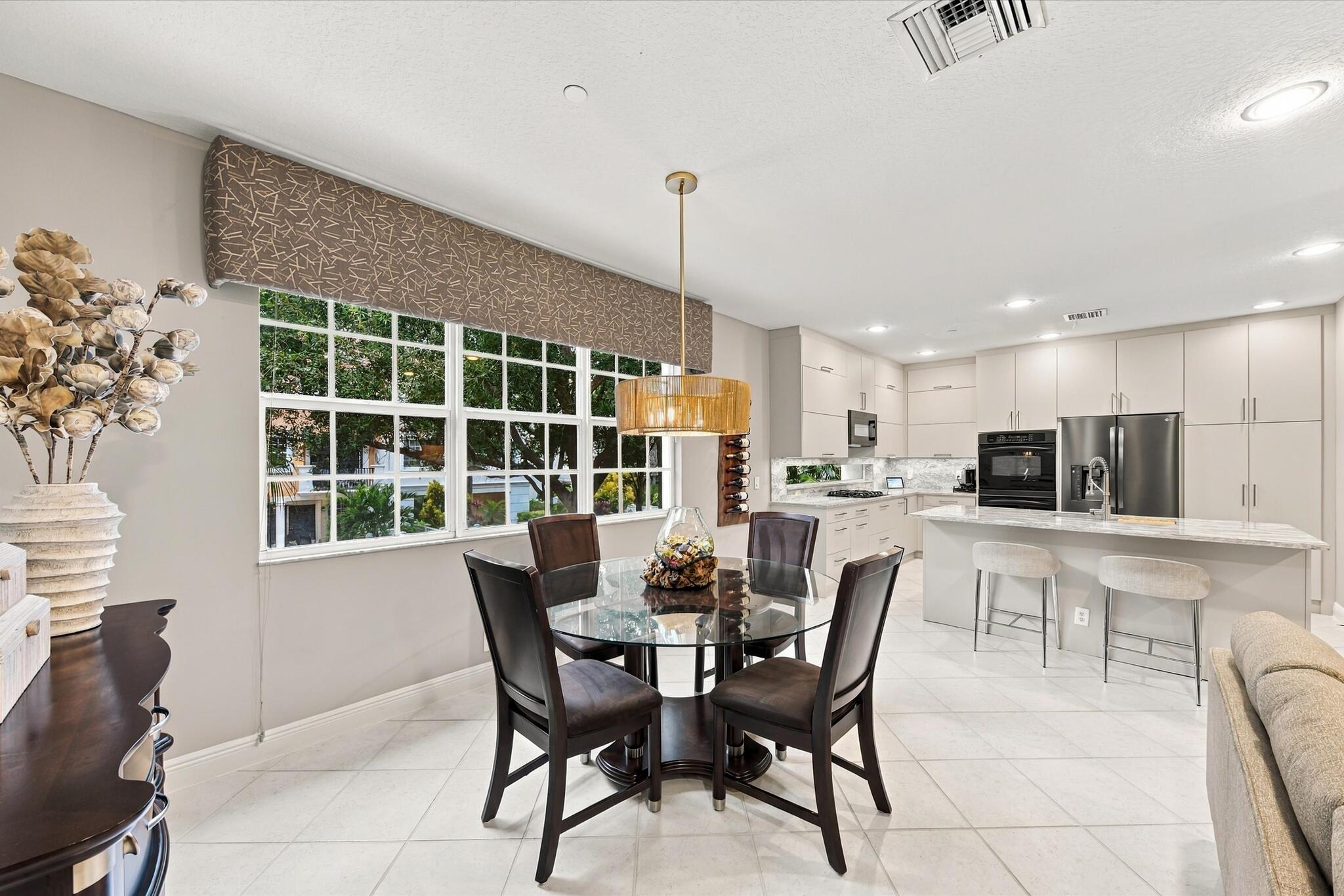 Kitchen featuring flat-panel cabinetry, a stone-surfaced kitchen island, built-in double wall ovens, a tile backsplash, and large-format tile flooring