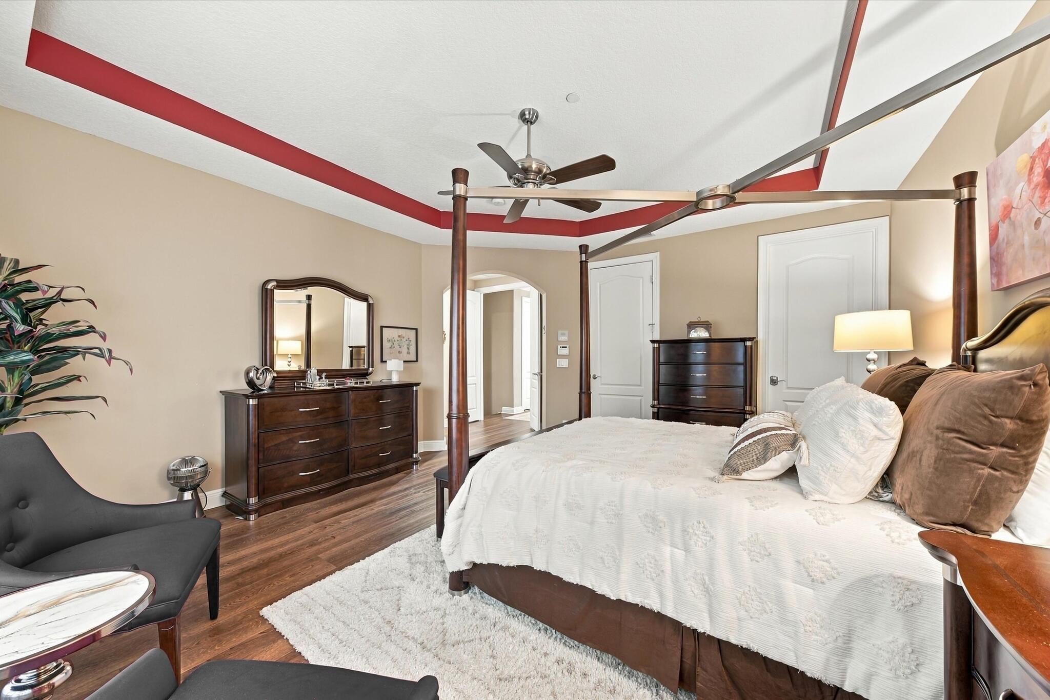 Tray ceiling with accent molding, wood-finish flooring, and a central ceiling fan