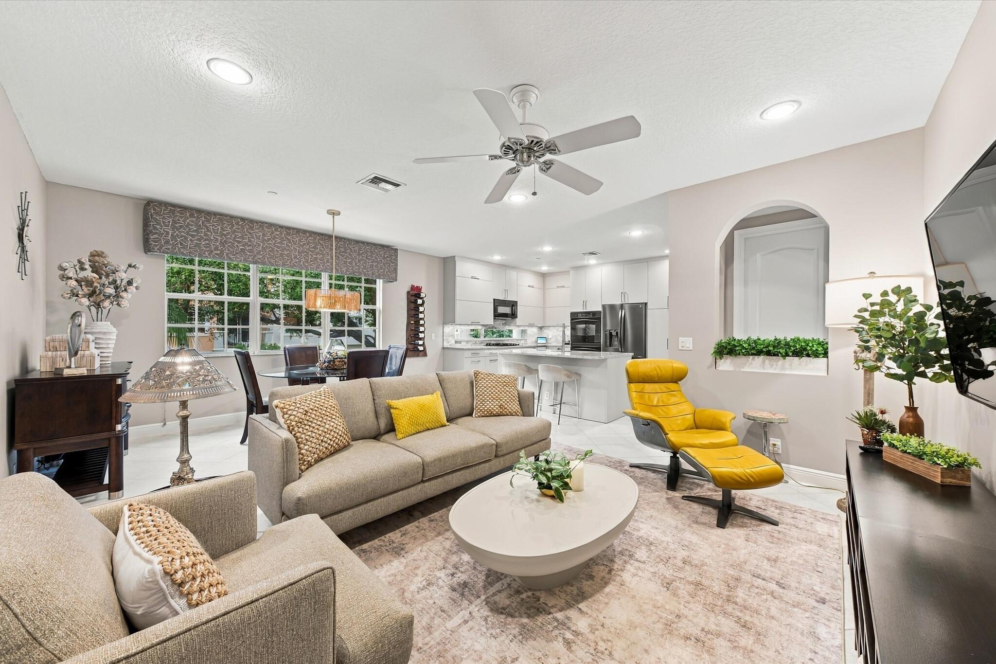 Open-concept interior featuring recessed lighting, a ceiling fan, a kitchen island with stone countertops, white flat-panel cabinetry, and an arched wall niche