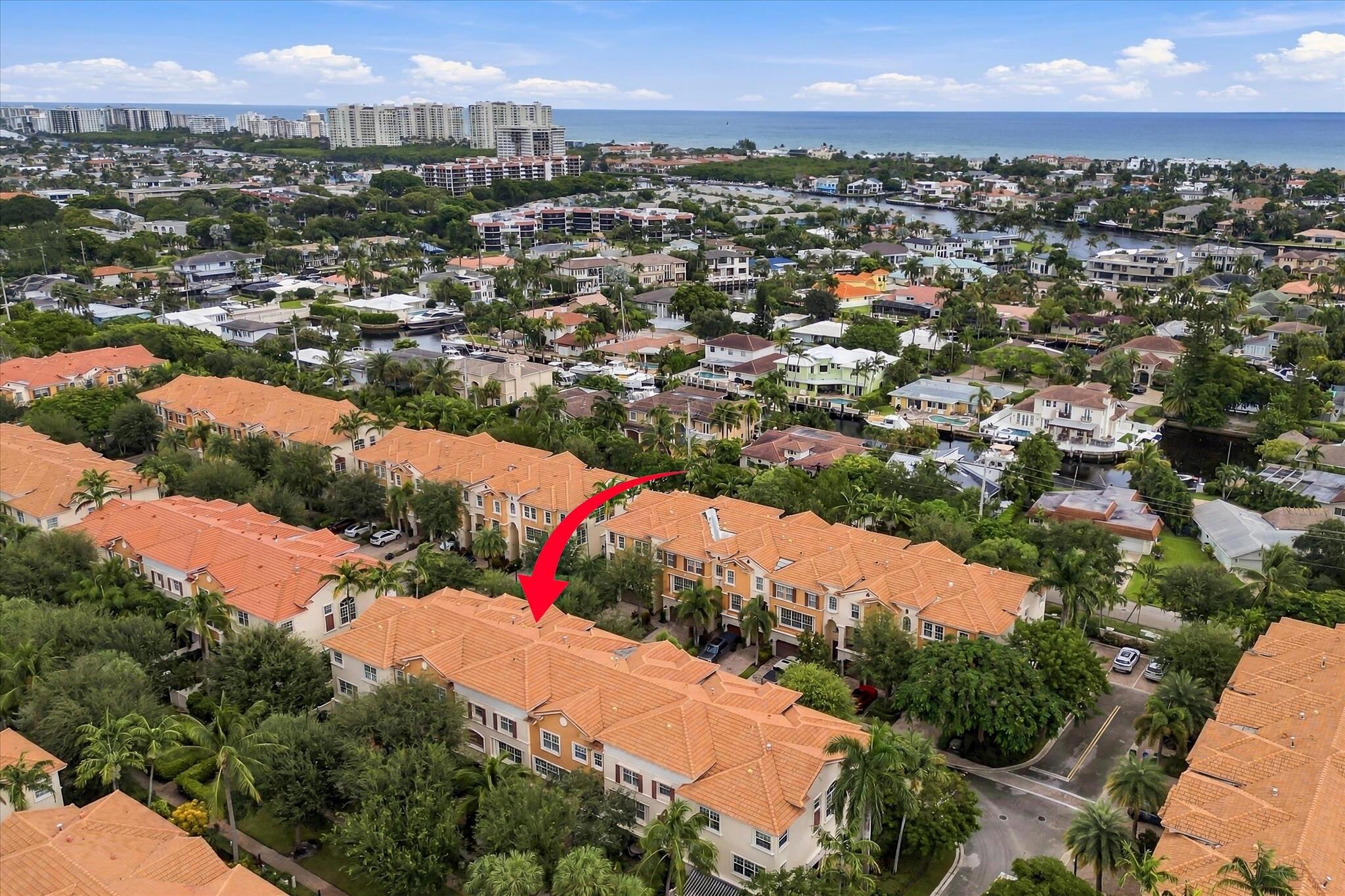 Aerial perspective of a multi-story residential building featuring a terracotta tile roof, stucco exterior, and mature landscaping