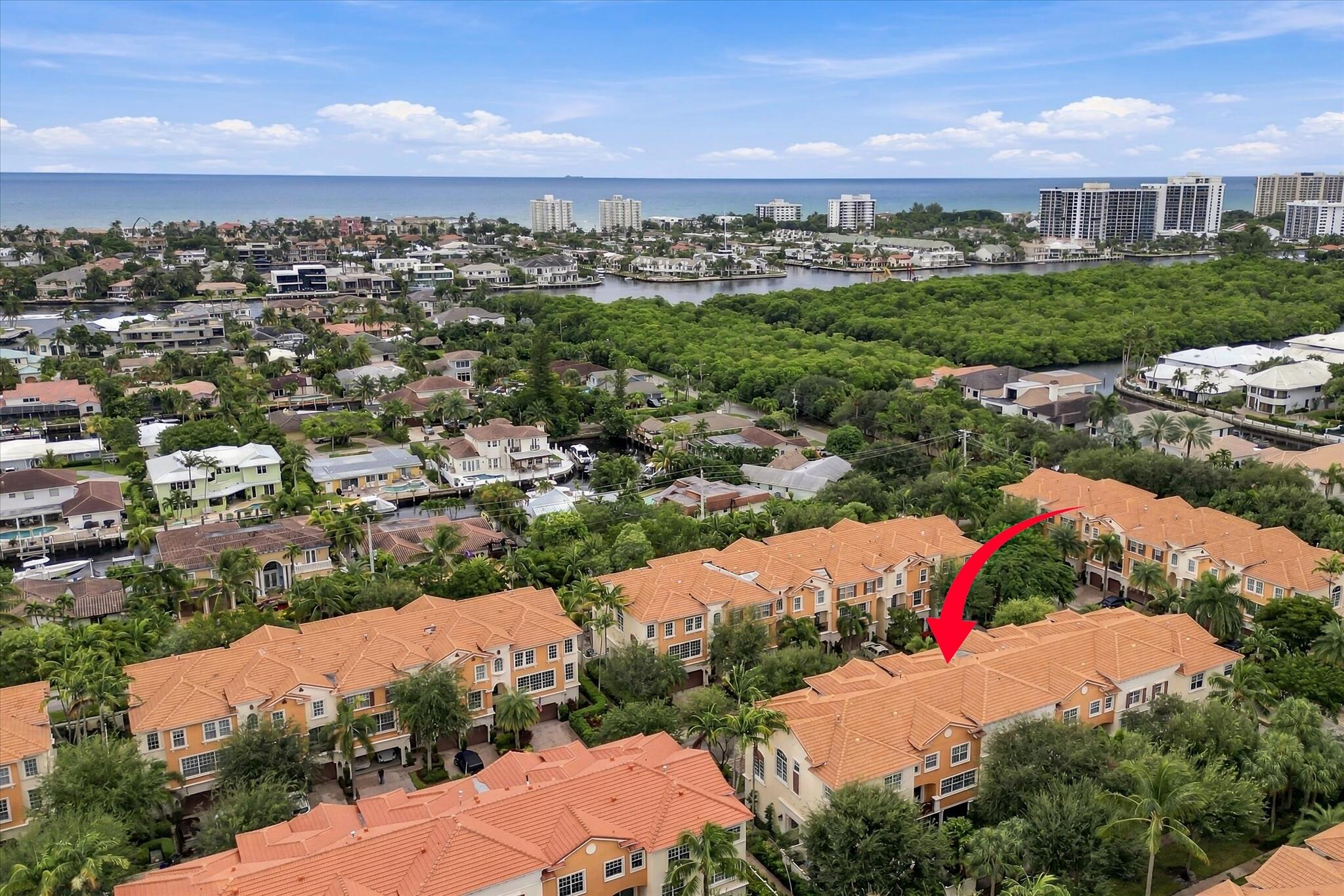 Aerial view of a multi-story residential structure featuring a clay tile roof and a stucco exterior, situated within a coastal landscape