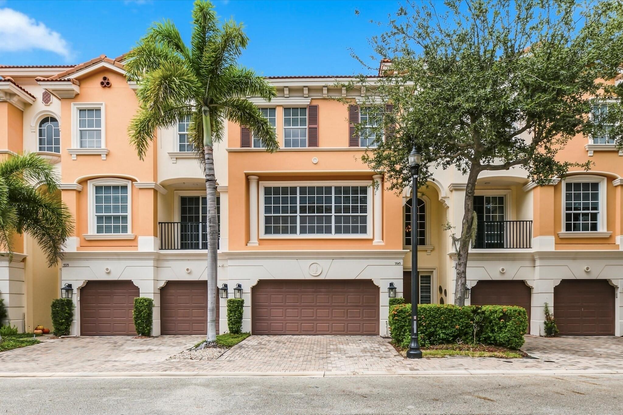 Mediterranean-style exterior featuring a multi-level facade, arched window detailing, wrought iron balcony railings, paved driveway, and attached multi-car garage