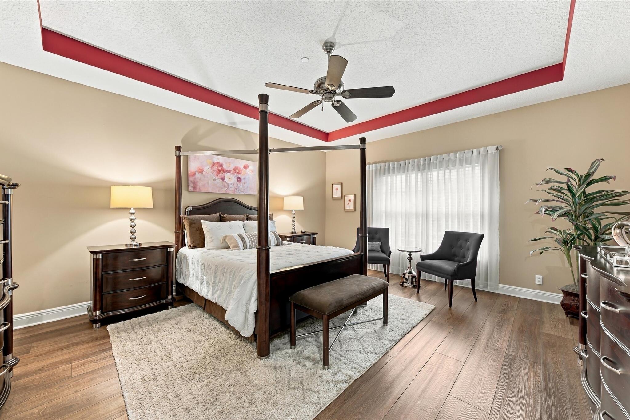 Tray ceiling with decorative inset molding, wood-finish flooring, and a multi-speed ceiling fan