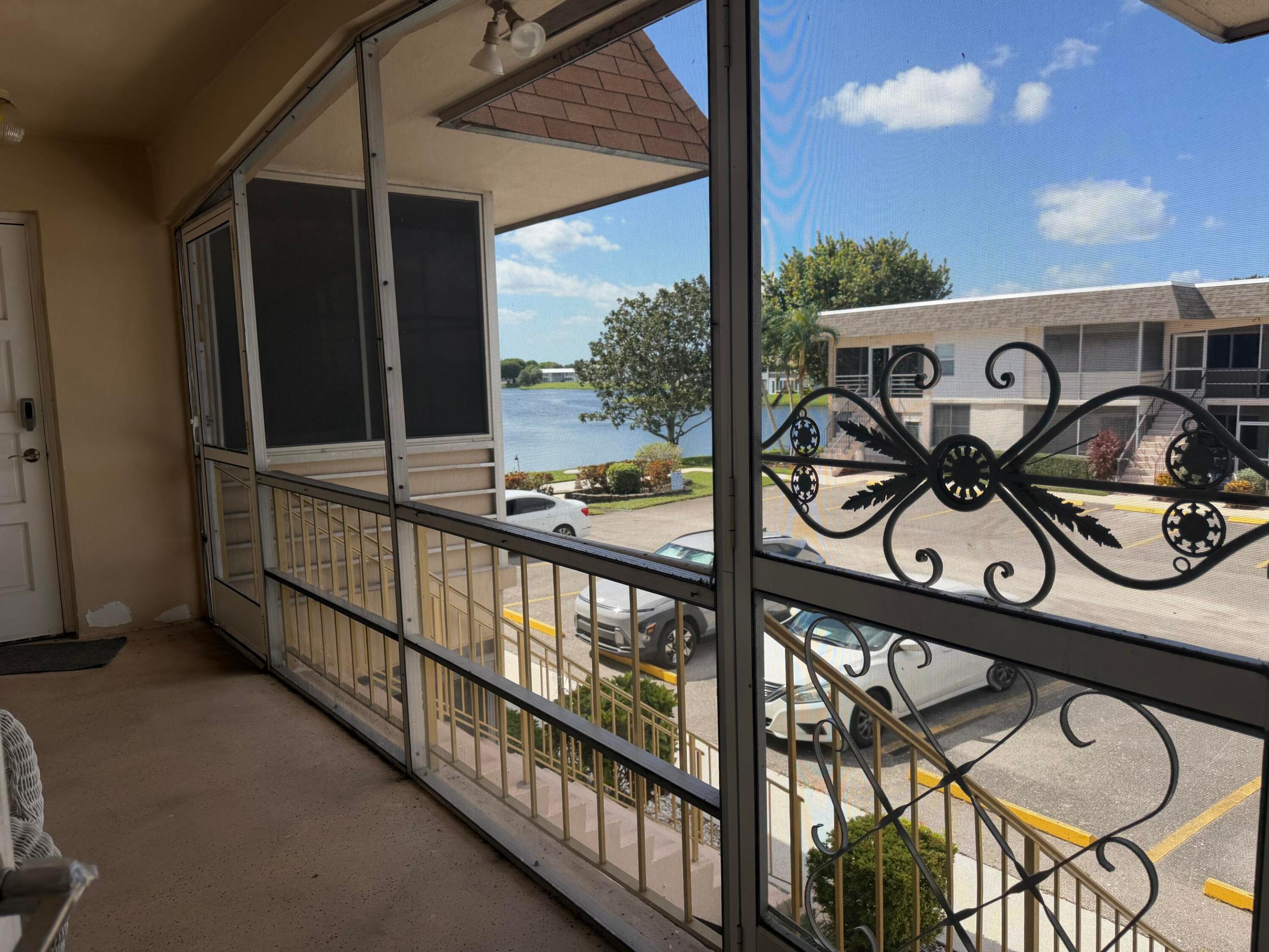 Screened-in balcony featuring decorative wrought iron scrollwork and a concrete floor