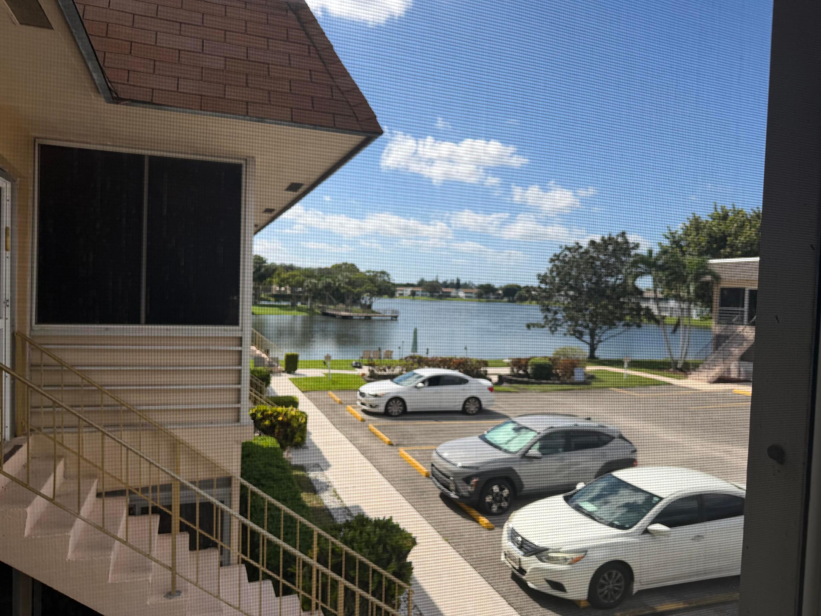 Exterior building elevation featuring metal railings, shingled roofing, and a waterfront setting Exterior building elevation featuring metal railings, shingled roofing, and a waterfront setting