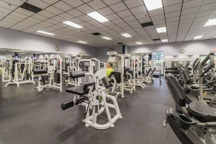 Fitness center featuring rubber flooring, recessed drop-ceiling grid lighting, and wall-to-wall mirrors