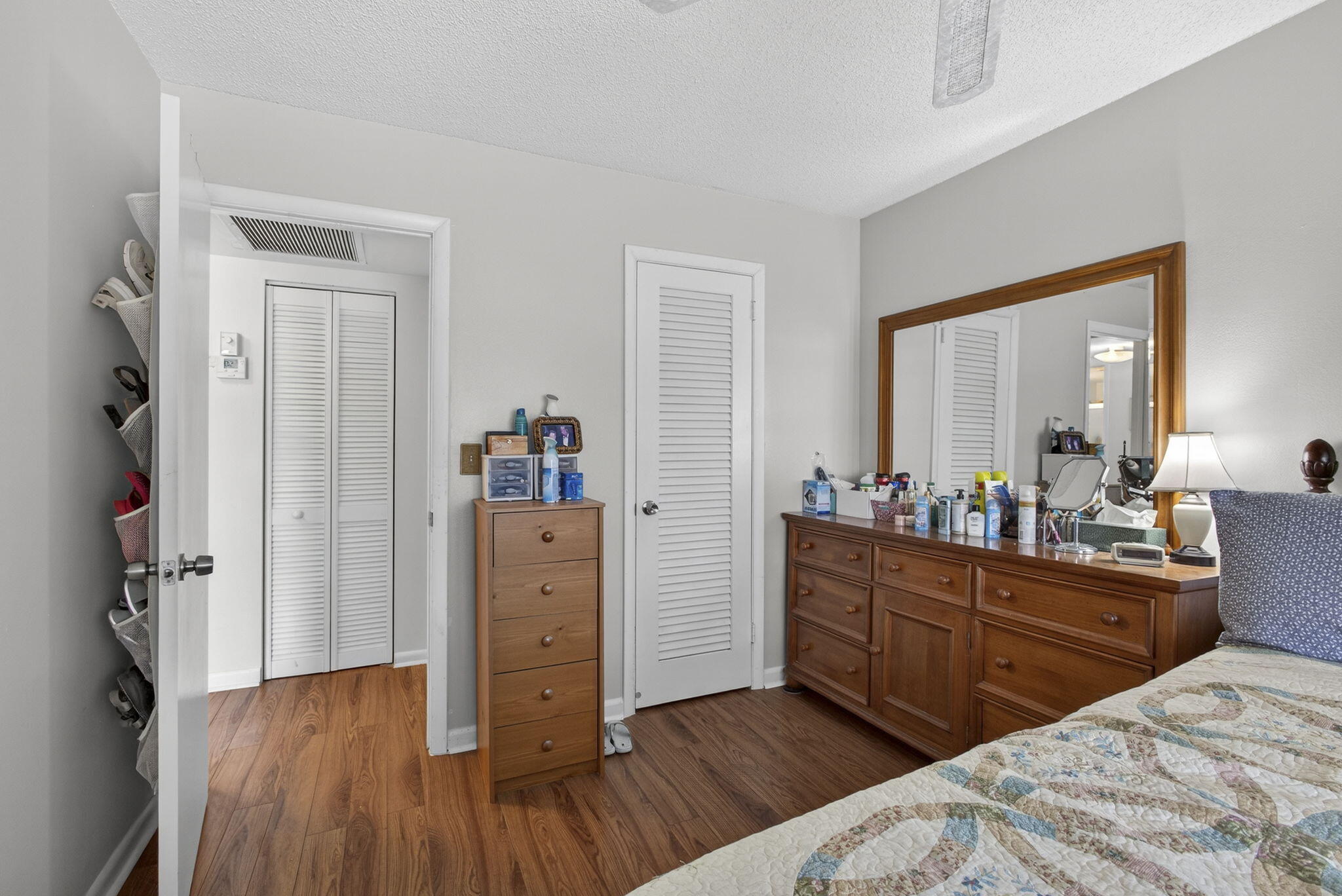 Room featuring wood-finish flooring, white louvered closet doors, and neutral wall tones