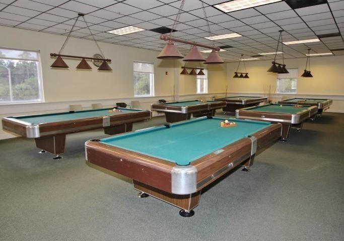 Recreation room featuring a grid ceiling, recessed panel lighting, and multiple suspended metal light fixtures