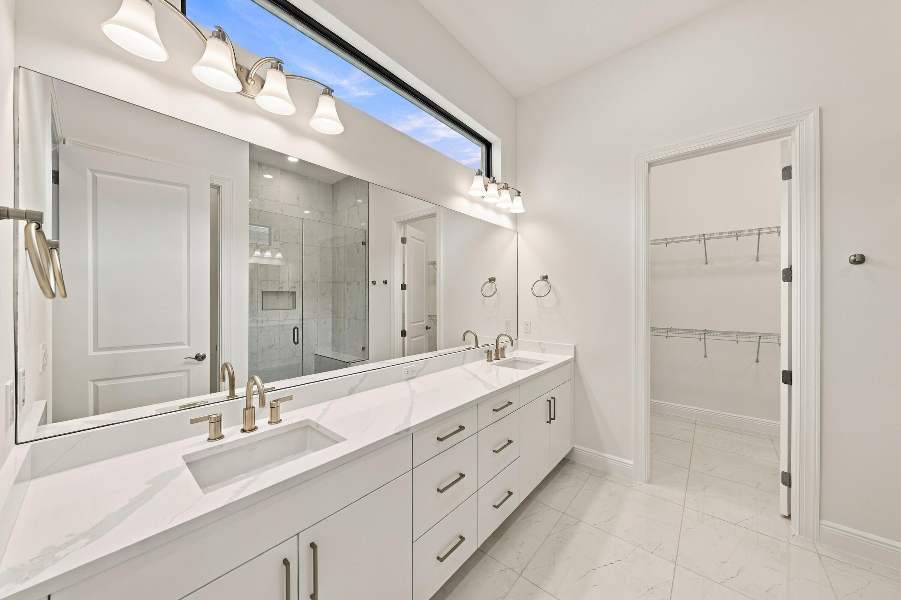 Primary bathroom with quartz countertops, double sinks with soft close drawers and cabinets and walk-in closet