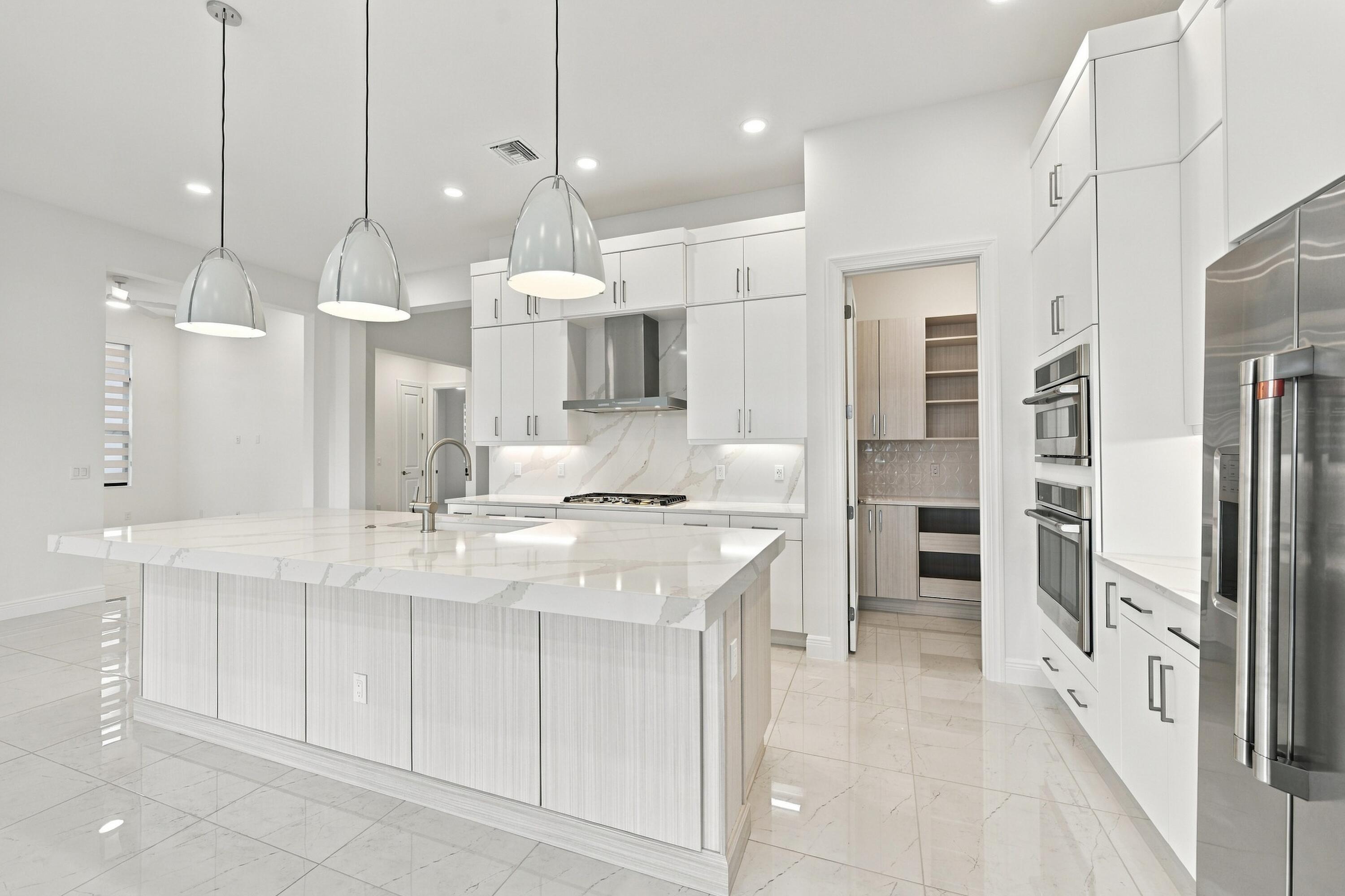 Oversized island with 3 inch upgraded quartz countertop, island pendant lights with GE cafe appliaces