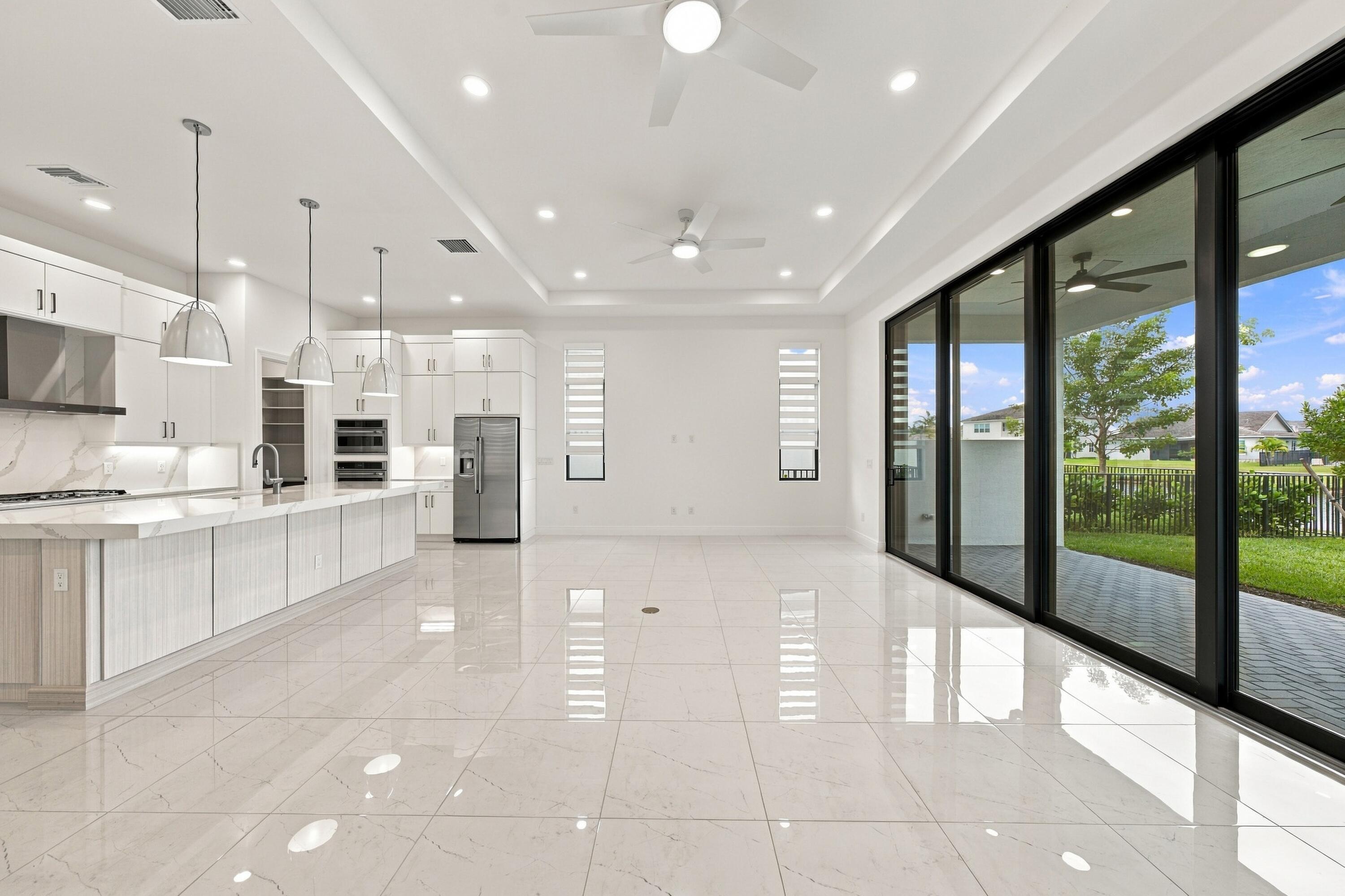 Great room with tray ceilings and upgraded 10ft high x 16ft long sliding glass doors, ceiling fans, island pendant lights