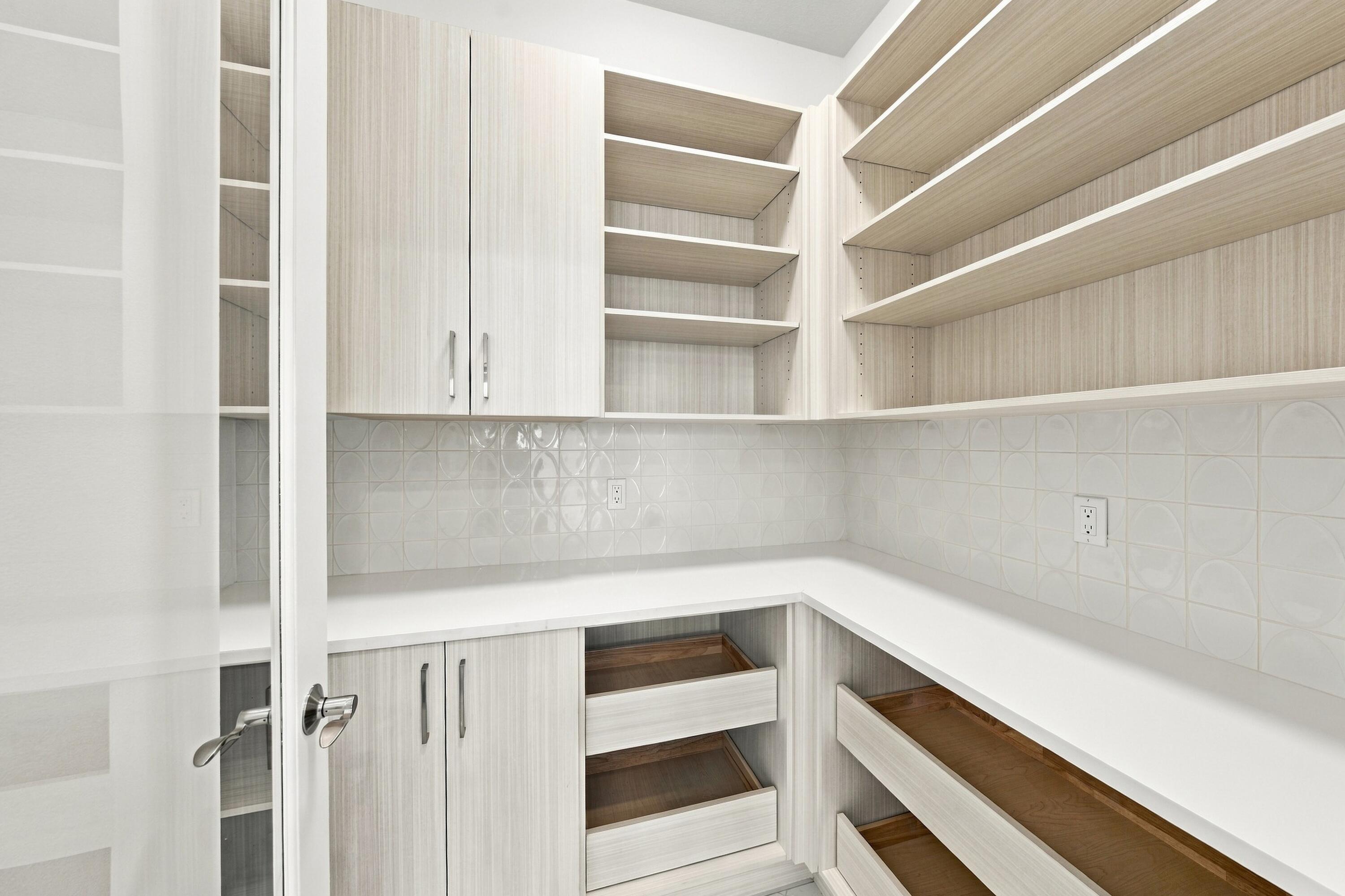 Walk in pantry with upgraded cabinets, drawers, countertops, backsplash and glass door