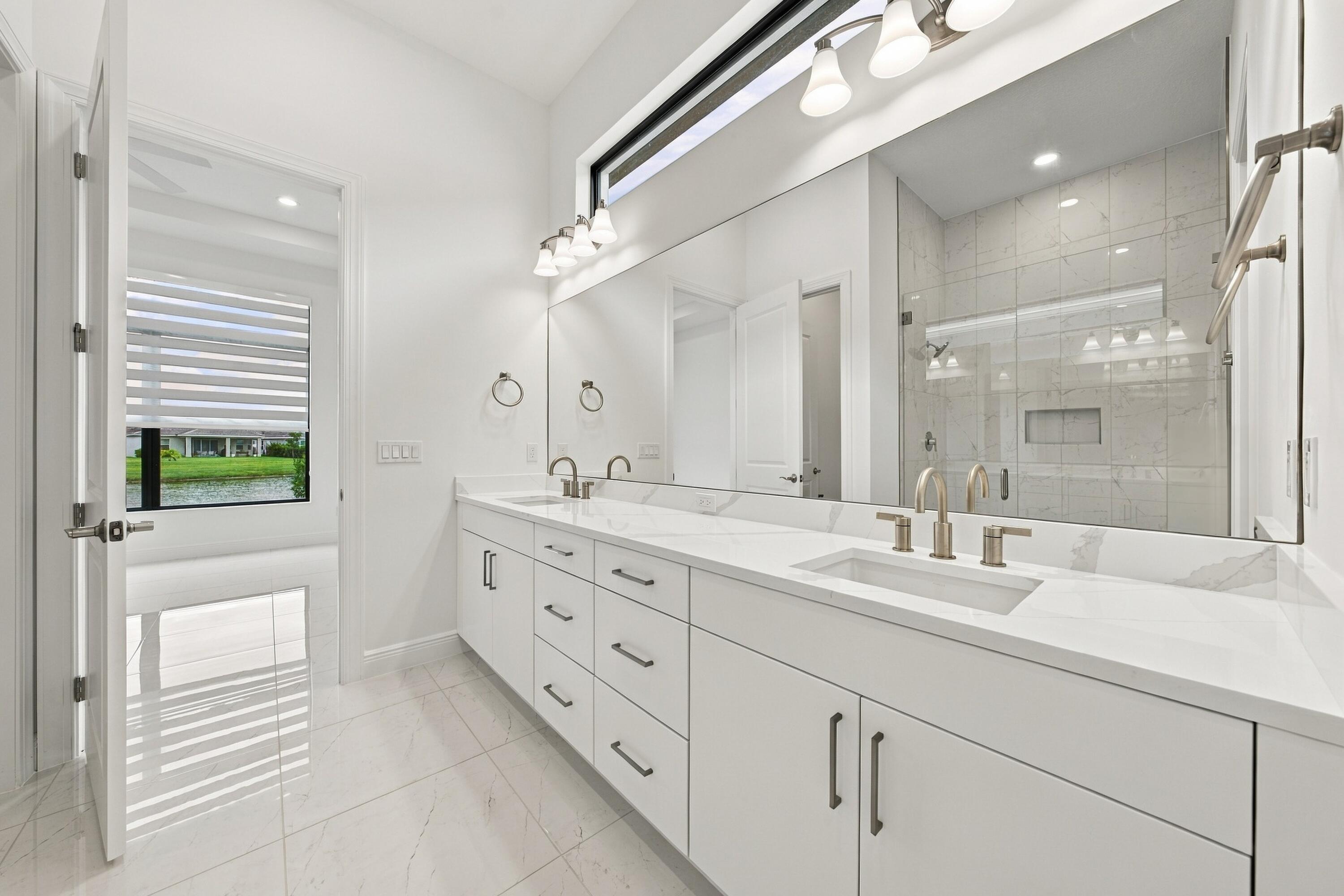Primary bathroom with double sinks and vanity lights, upgraded cabinets and quartz countertops, transom window