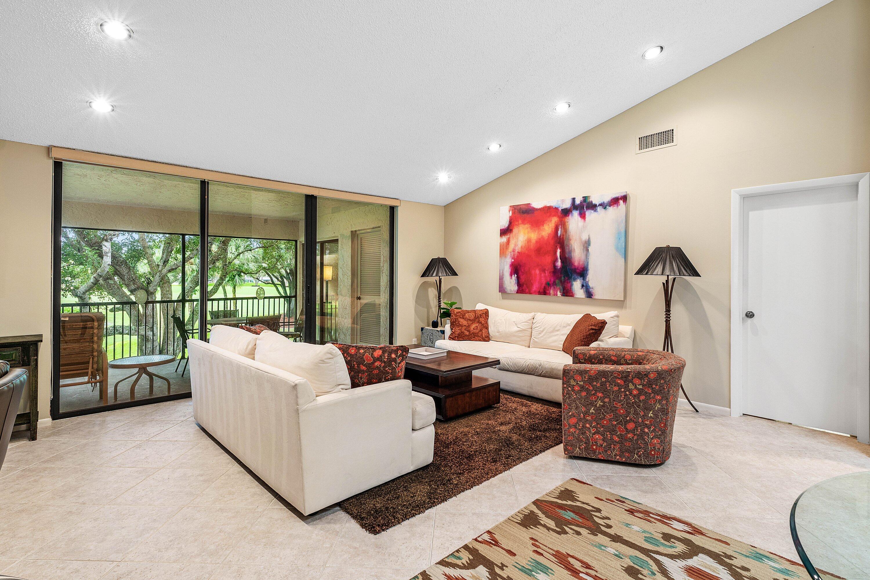 Vaulted ceilings, large sliding glass doors, recessed lighting, and tile flooring