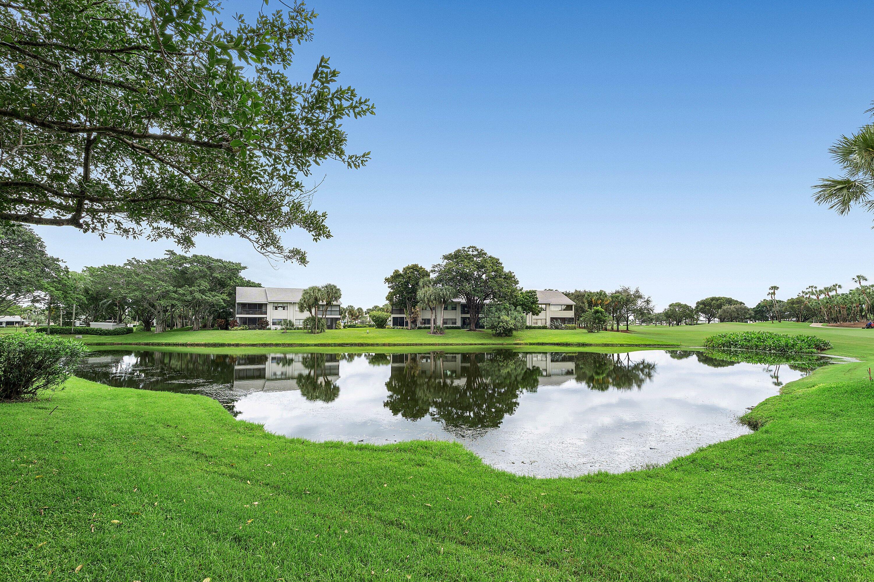 Expansive water feature bordered by manicured lawn, mature trees, and landscaping