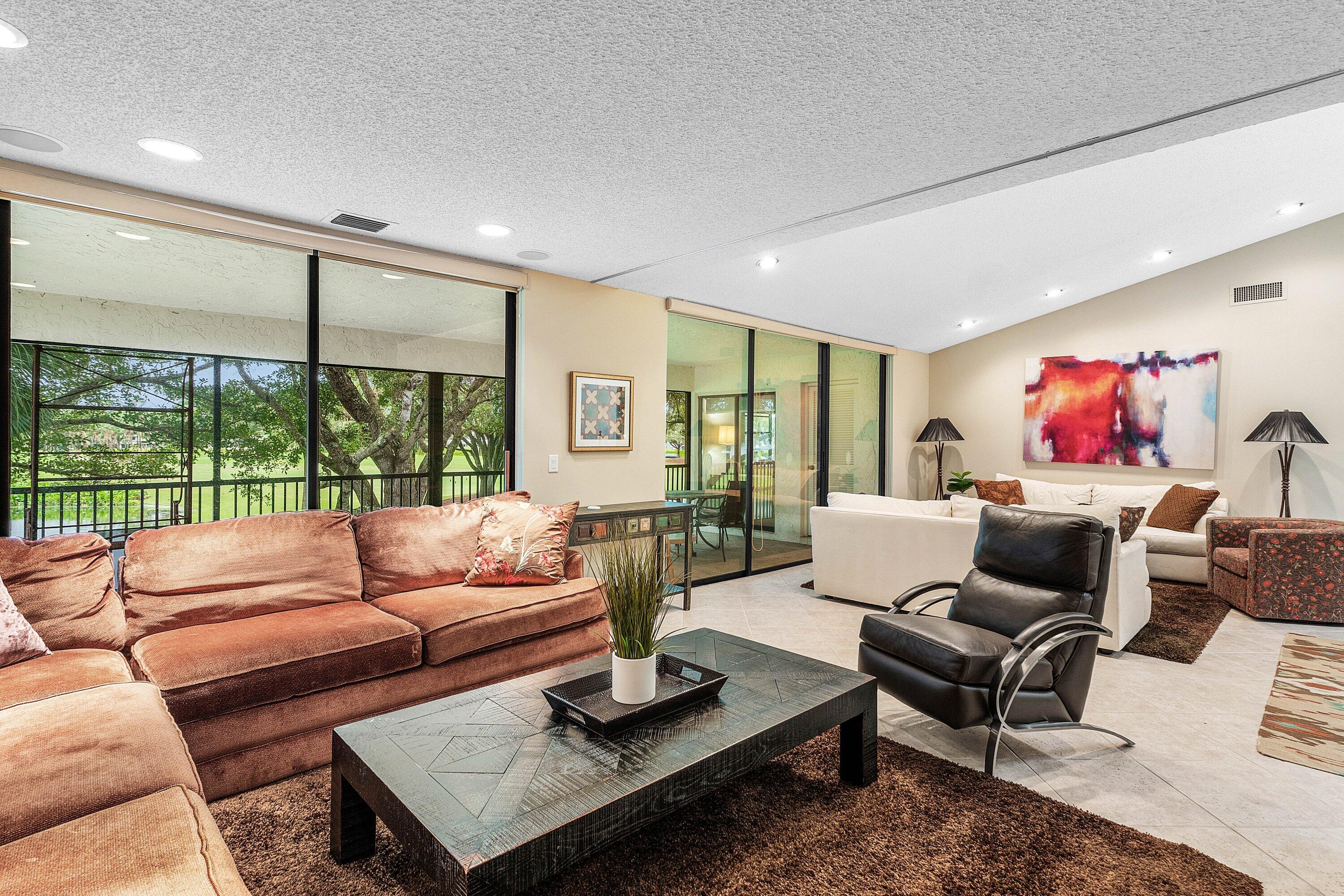 Vaulted ceilings with recessed lighting, expansive floor-to-ceiling glass doors, and light-toned tile flooring