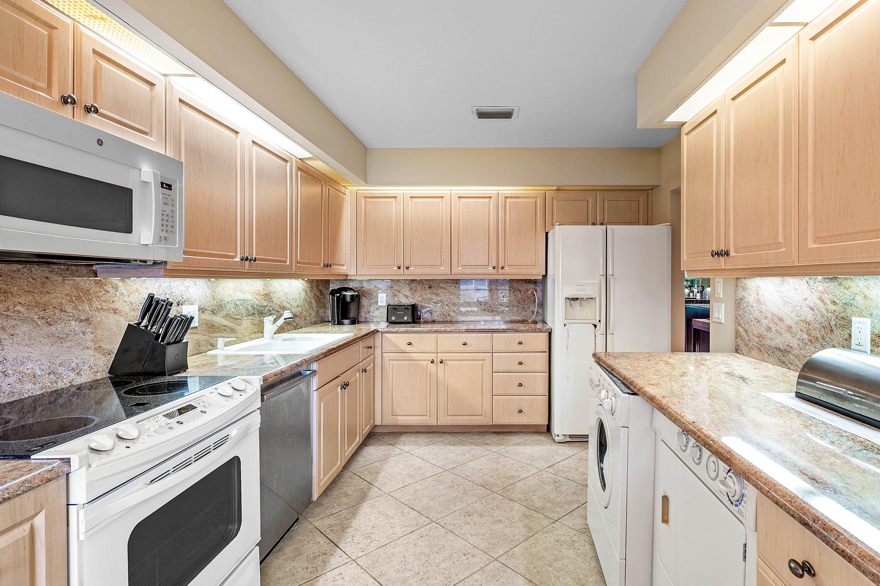 Kitchen featuring shaker-style light wood cabinetry, stone countertops, integrated stone backsplash, ceramic tile flooring, and under-cabinet lighting