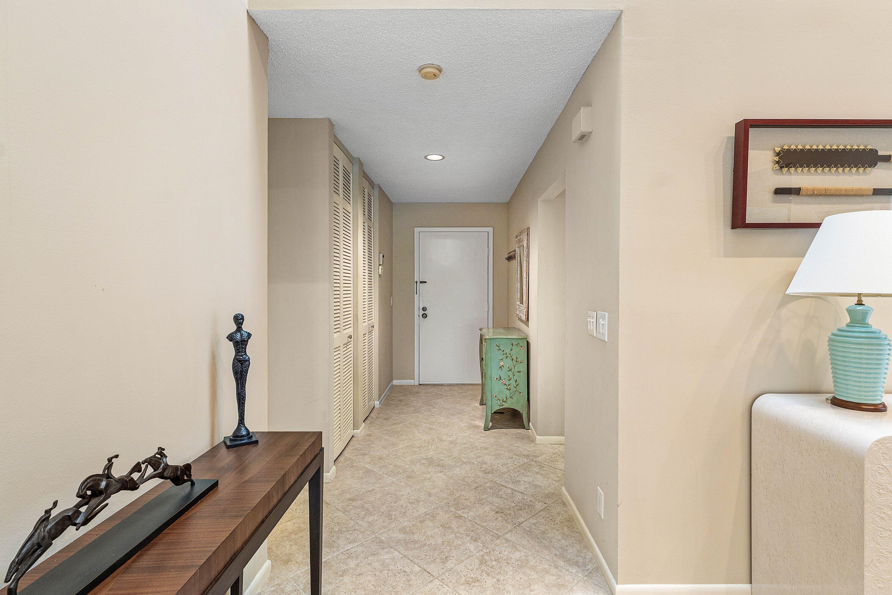 Entryway featuring neutral tile flooring, built-in floor-to-ceiling louvered cabinetry, and recessed lighting