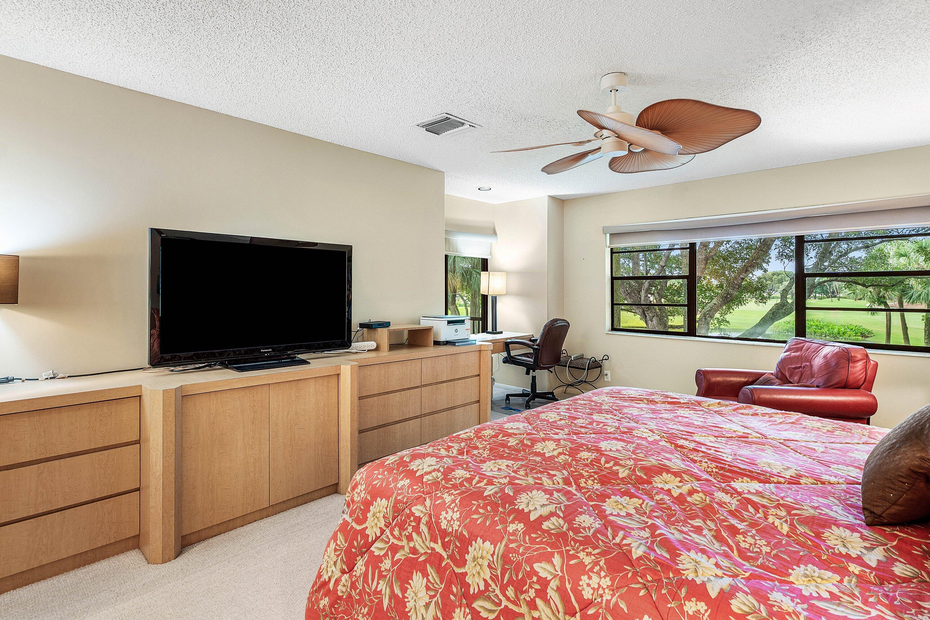 Built-in light-toned cabinetry, multi-blade ceiling fan, and large windows with landscape scenery